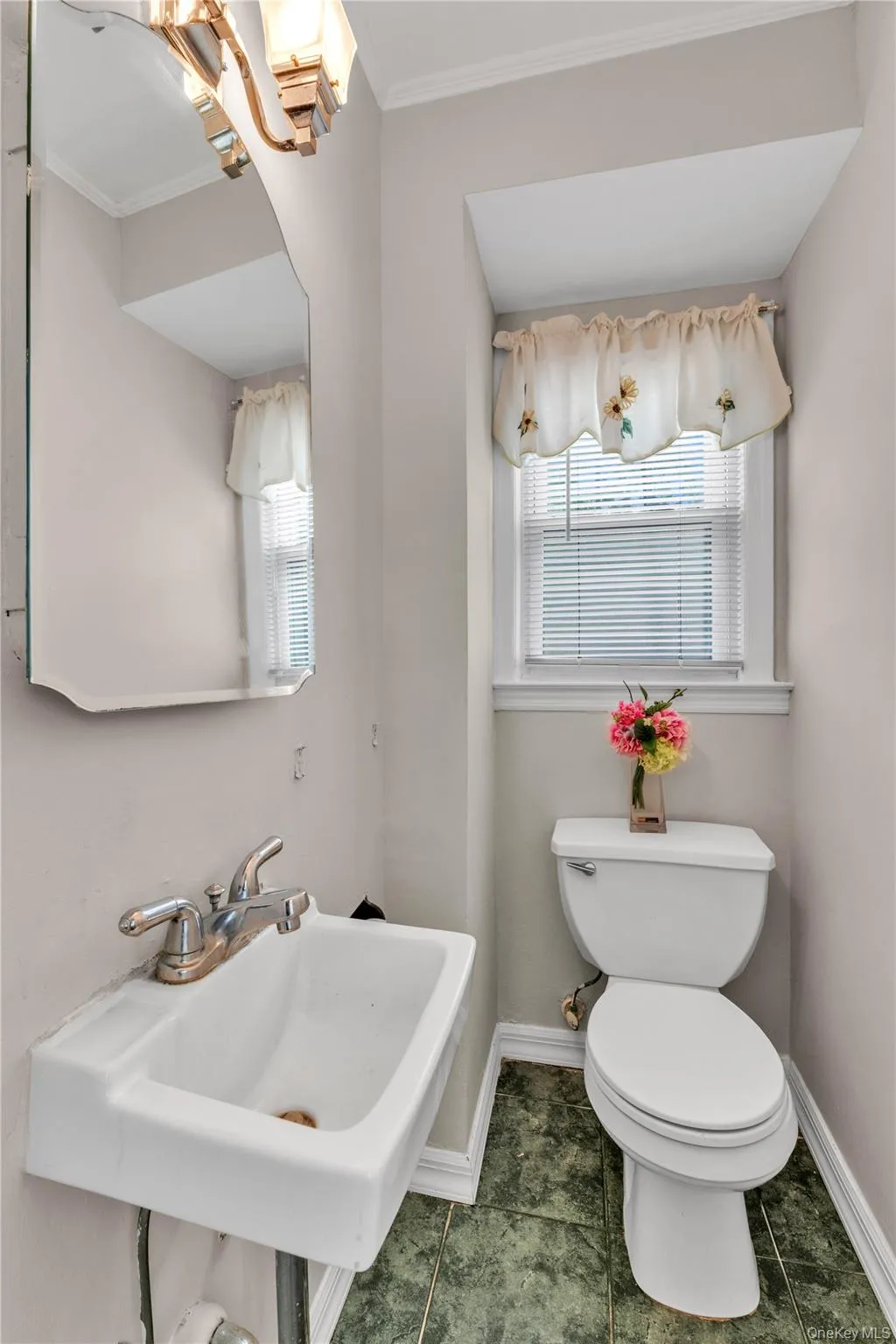 Compact bathroom featuring a white wall-mounted sink, a white toilet, and green-patterned tile flooring Compact bathroom featuring a white wall-mounted sink, a white toilet, and green-patterned tile flooring