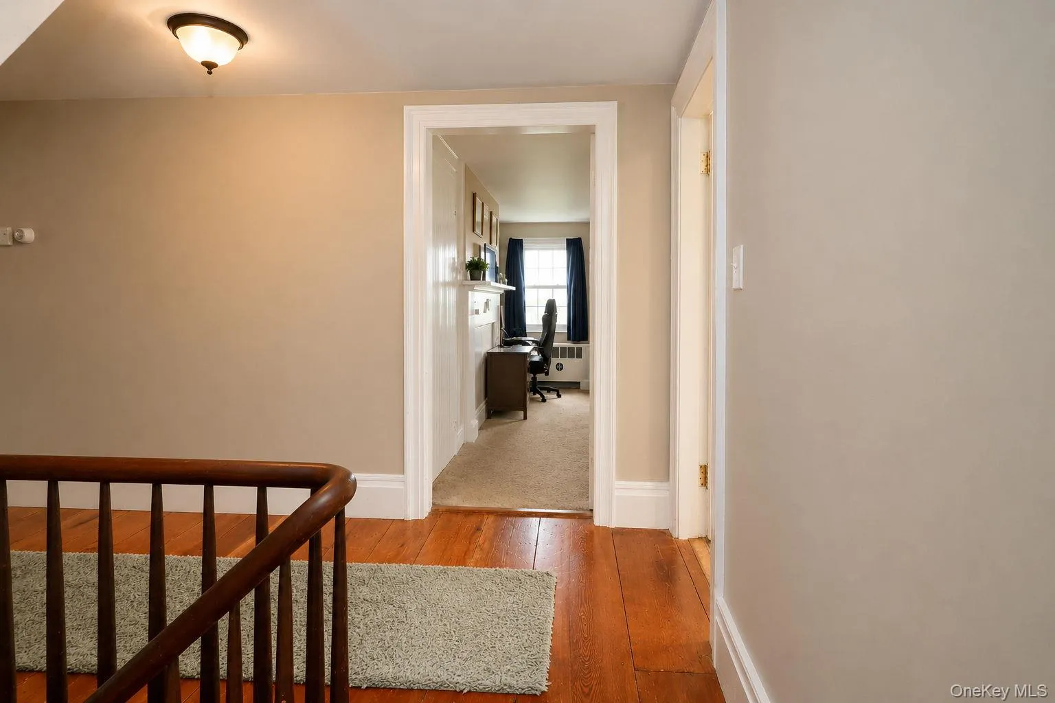 View of the upstairs stairway railing, original wide wood plank flooring and a bedroom View of the upstairs stairway railing, original wide wood plank flooring and a bedroom