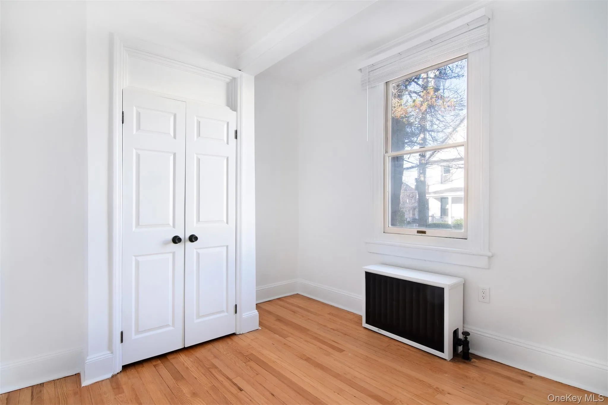 Bedroom featuring light hardwood flooring and radiator heating unit Bedroom featuring light hardwood flooring and radiator heating unit