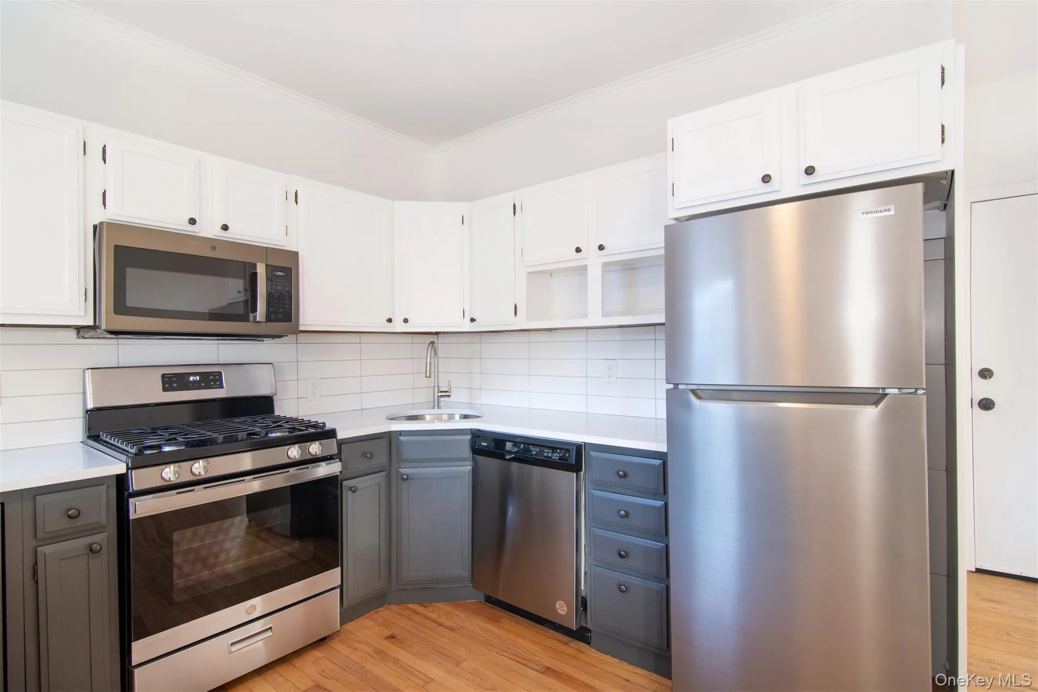 Kitchen with sink, white cabinets, stainless steel appliances, and light hardwood floors Kitchen with sink, white cabinets, stainless steel appliances, and light hardwood floors