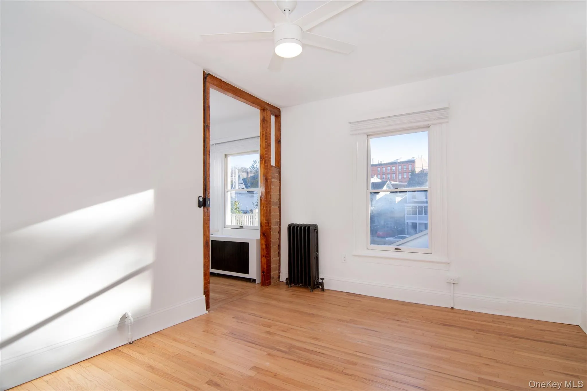 Livingroom with light hardwood floors, ceiling fan, a healthy amount of sunlight, and radiator heating unit Livingroom with light hardwood floors, ceiling fan, a healthy amount of sunlight, and radiator heating unit