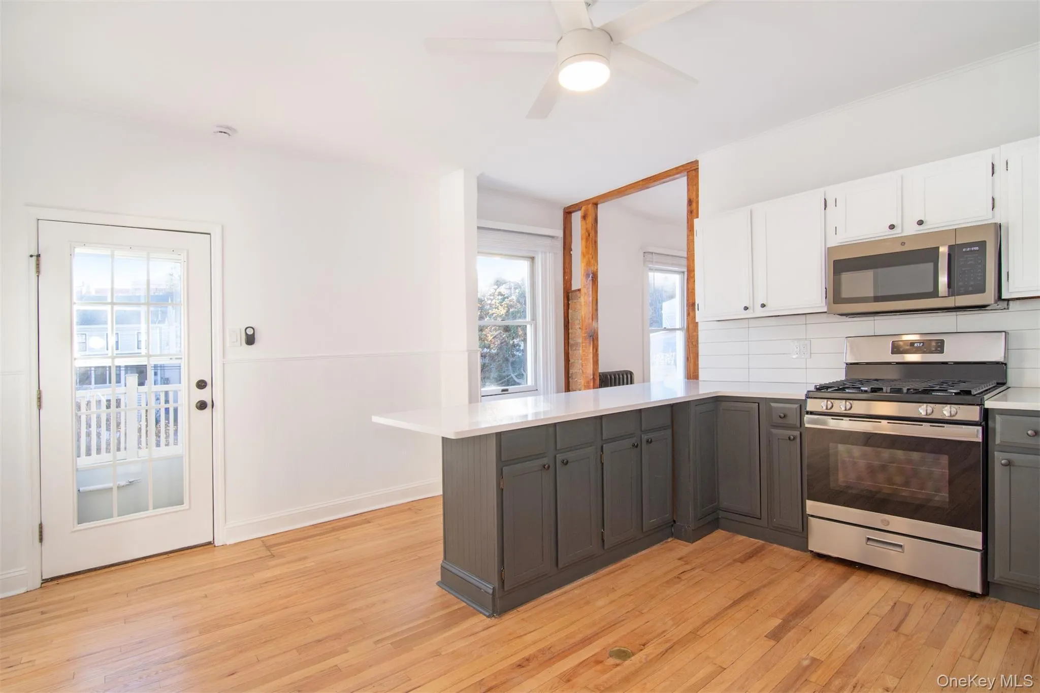 Kitchen with kitchen peninsula, backsplash, stainless steel appliances, white cabinets, and light hardwood floors Kitchen with kitchen peninsula, backsplash, stainless steel appliances, white cabinets, and light hardwood floors
