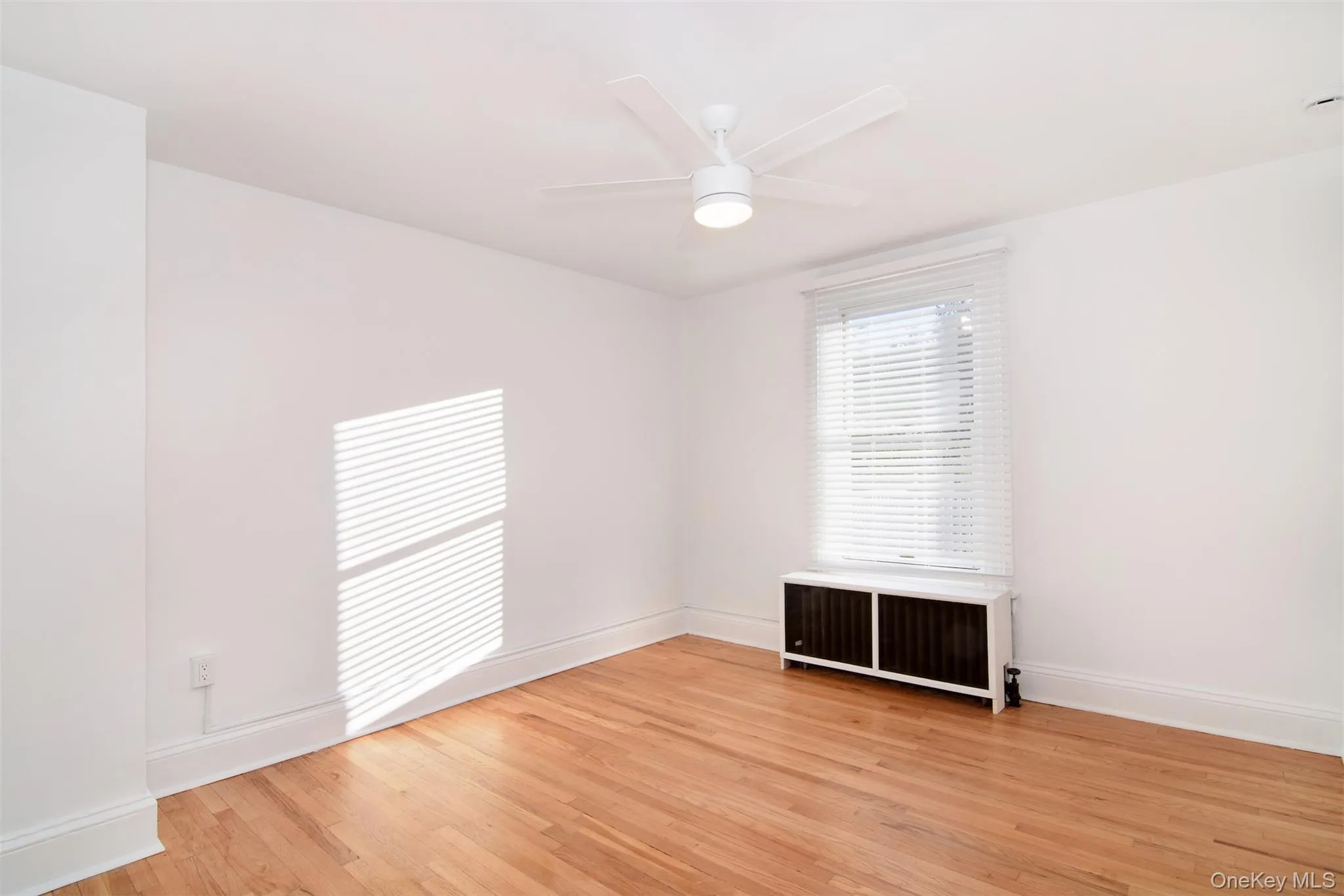 Bedroom with ceiling fan, radiator heating unit, and hardwood flooring Bedroom with ceiling fan, radiator heating unit, and hardwood flooring