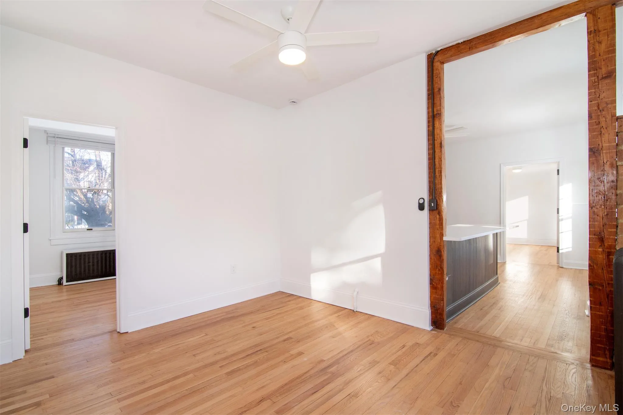Living room with radiator, ceiling fan, and light hardwood flooring Living room with radiator, ceiling fan, and light hardwood flooring