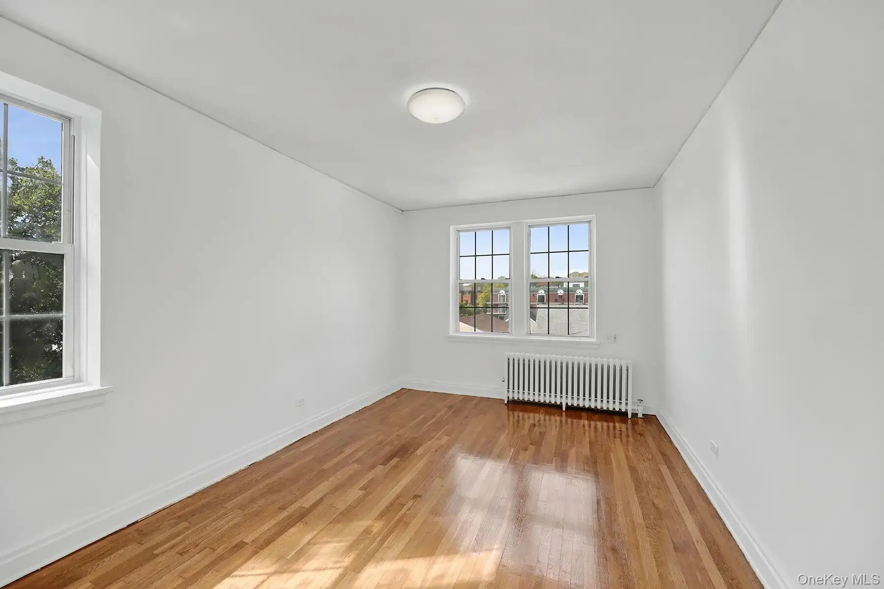 Hardwood flooring throughout a bright room featuring white walls and trim Hardwood flooring throughout a bright room featuring white walls and trim