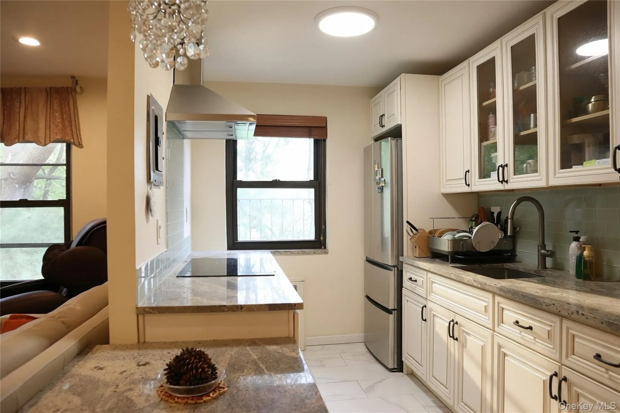 Updated kitchen featuring light-toned cabinetry, stainless steel appliances, a tile backsplash, and stone countertops Updated kitchen featuring light-toned cabinetry, stainless steel appliances, a tile backsplash, and stone countertops