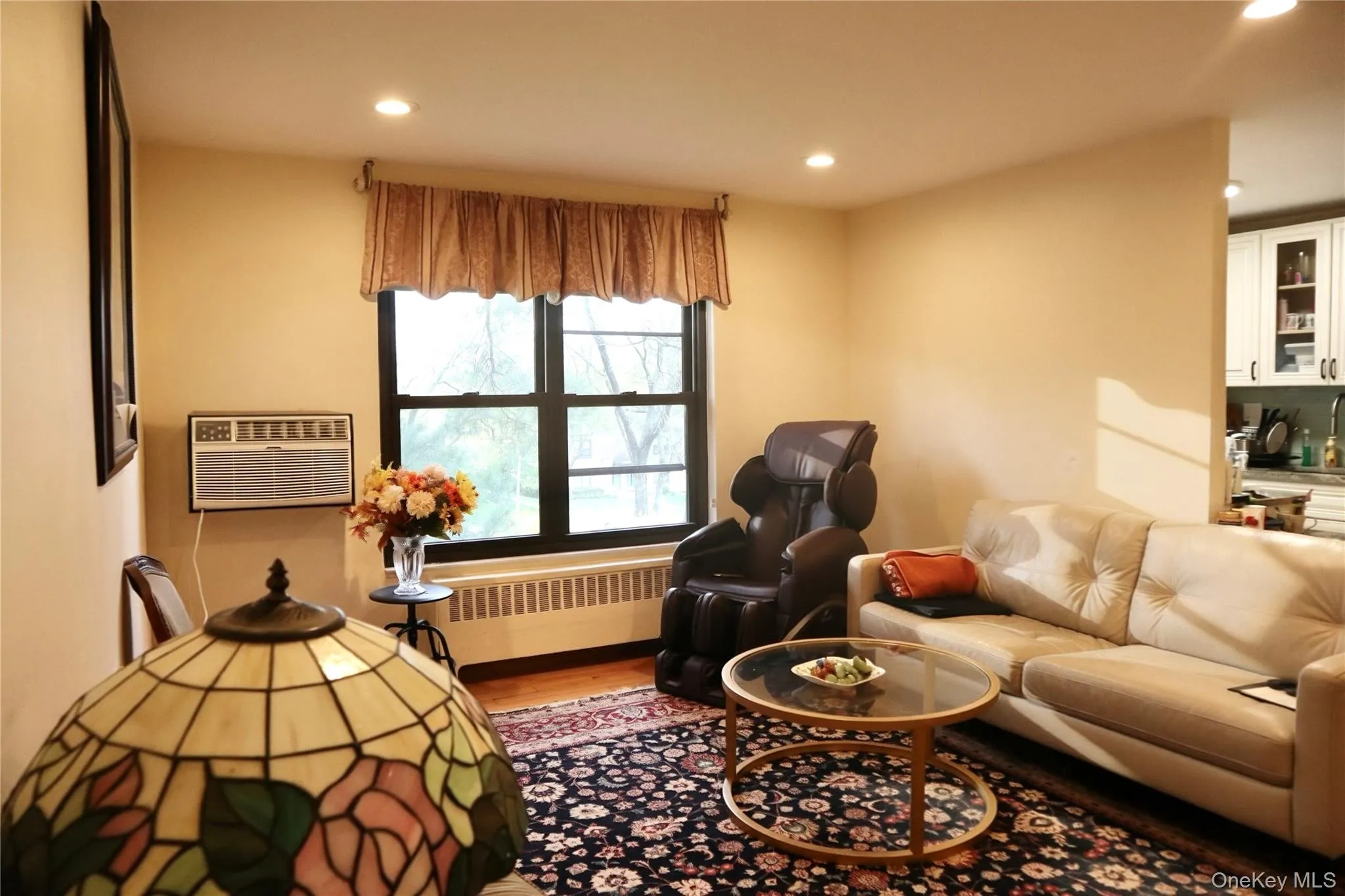Living area featuring recessed lighting, a large multi-pane window, hardwood flooring, and a radiator with a cover Living area featuring recessed lighting, a large multi-pane window, hardwood flooring, and a radiator with a cover