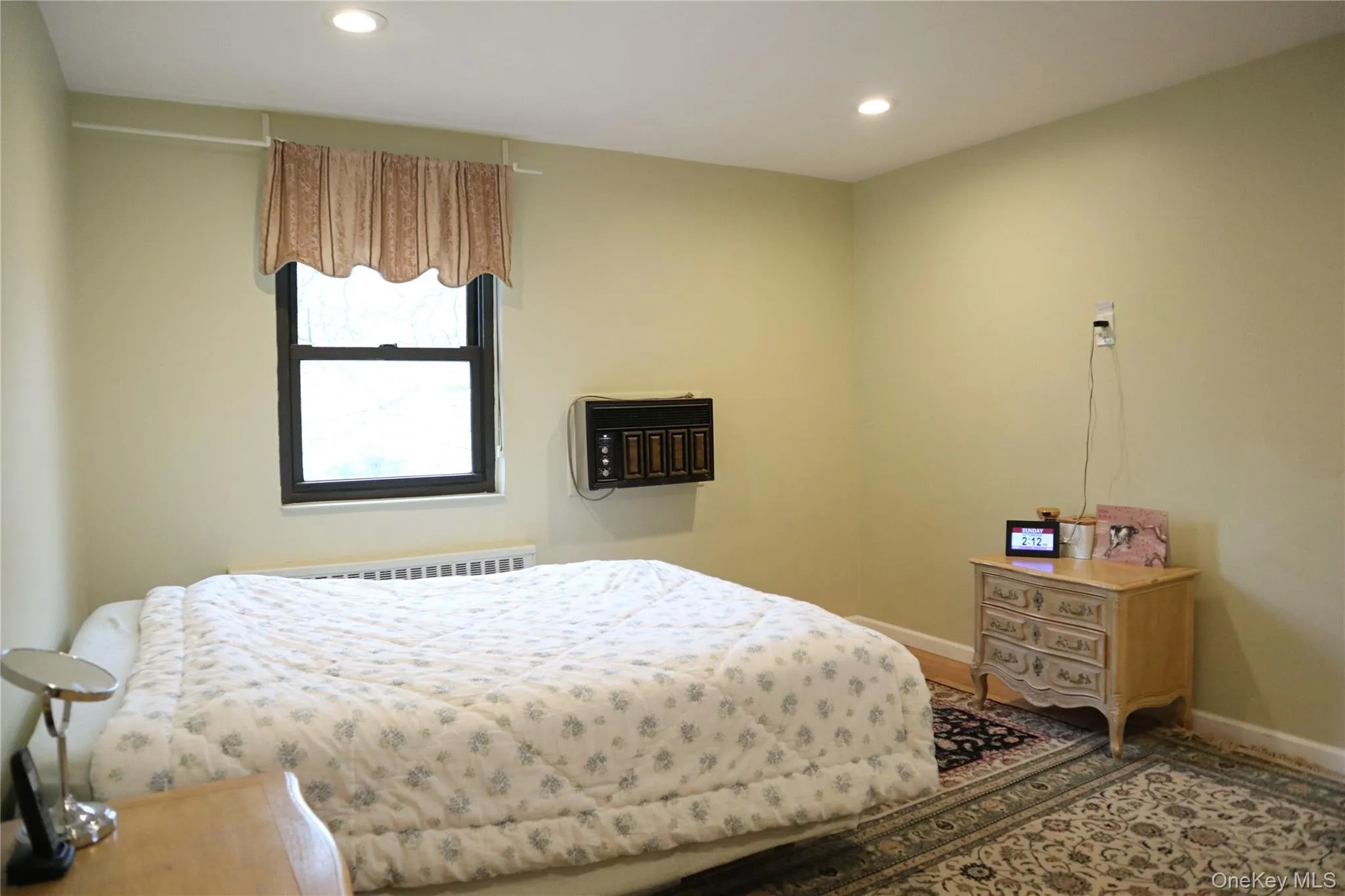 Recessed ceiling lighting illuminates this space featuring a window with valance, wall-mounted air conditioning unit, and baseboard heating Recessed ceiling lighting illuminates this space featuring a window with valance, wall-mounted air conditioning unit, and baseboard heating