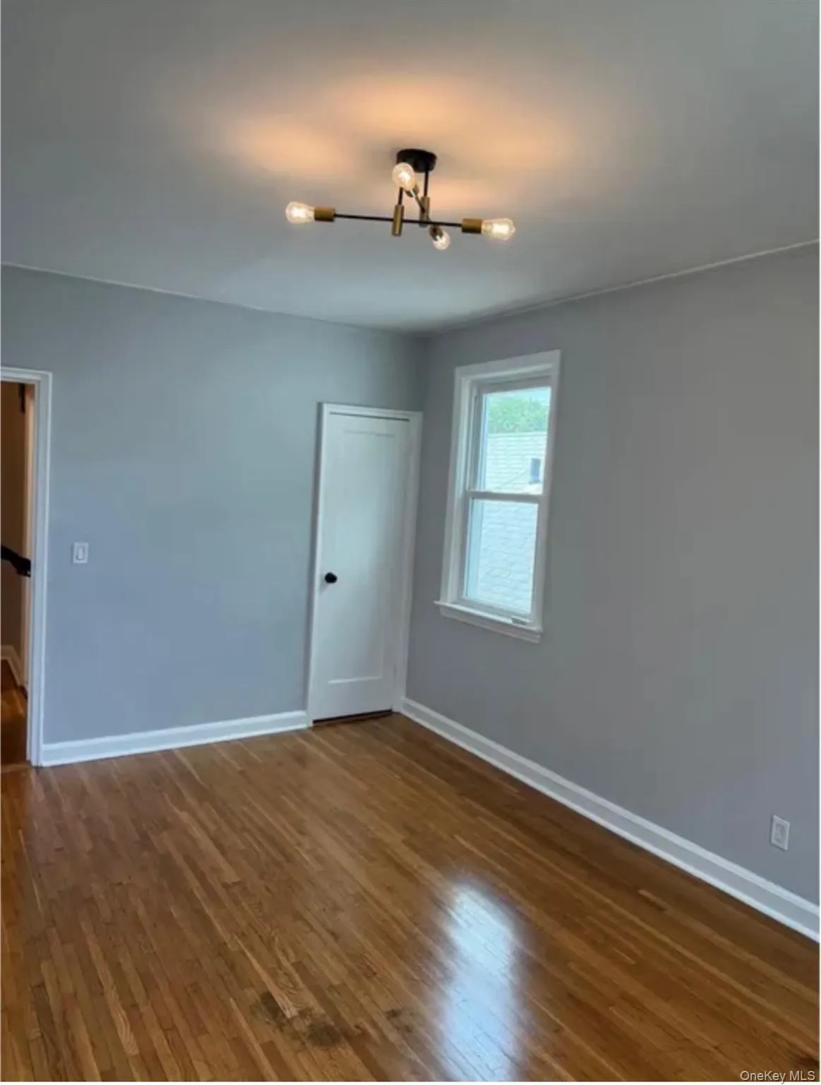 wood flooring throughout featuring light gray wall finishes, white trim, and a contemporary ceiling fixture wood flooring throughout featuring light gray wall finishes, white trim, and a contemporary ceiling fixture