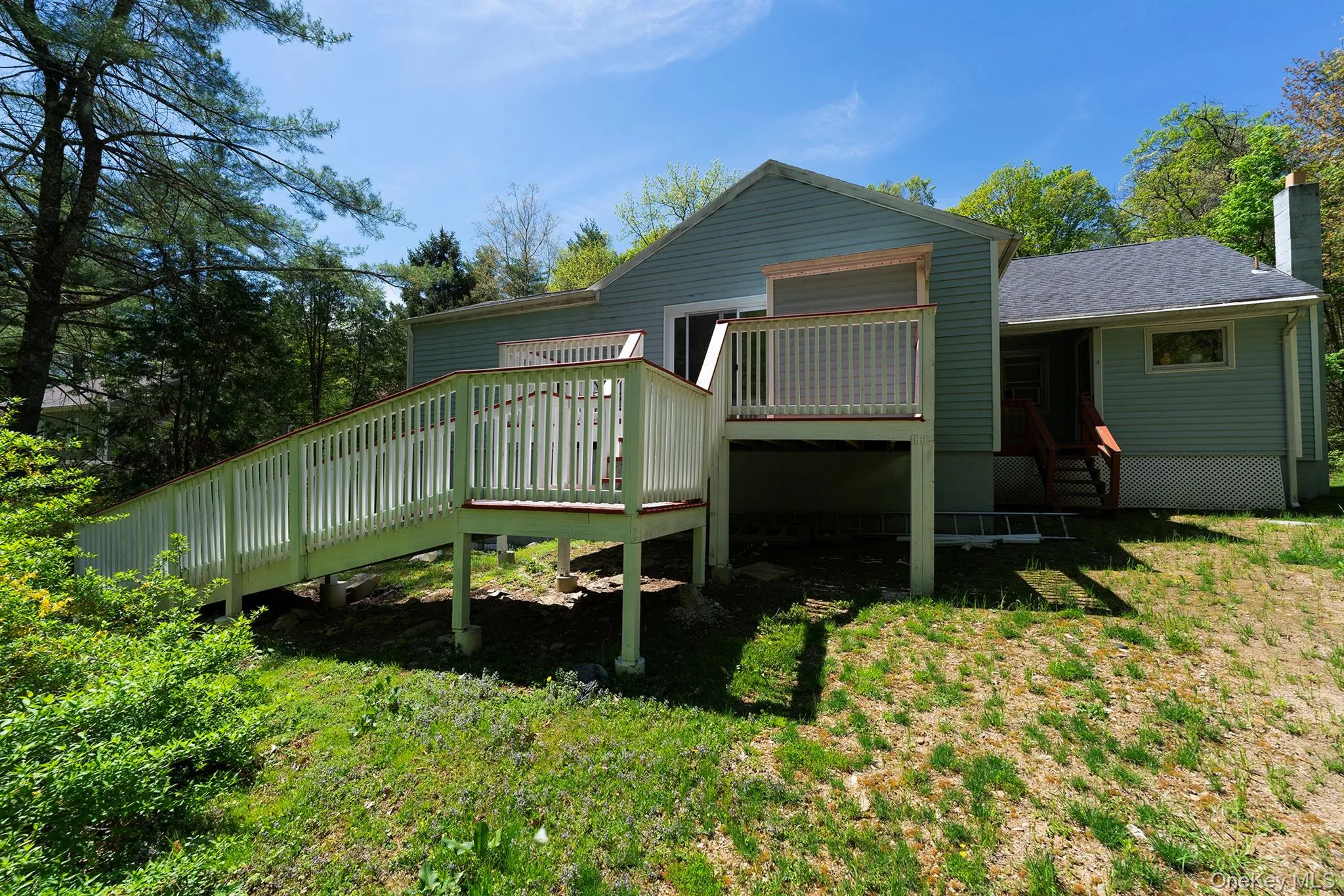 Back of house featuring a deck, a chimney, and a shingled roof Back of house featuring a deck, a chimney, and a shingled roof