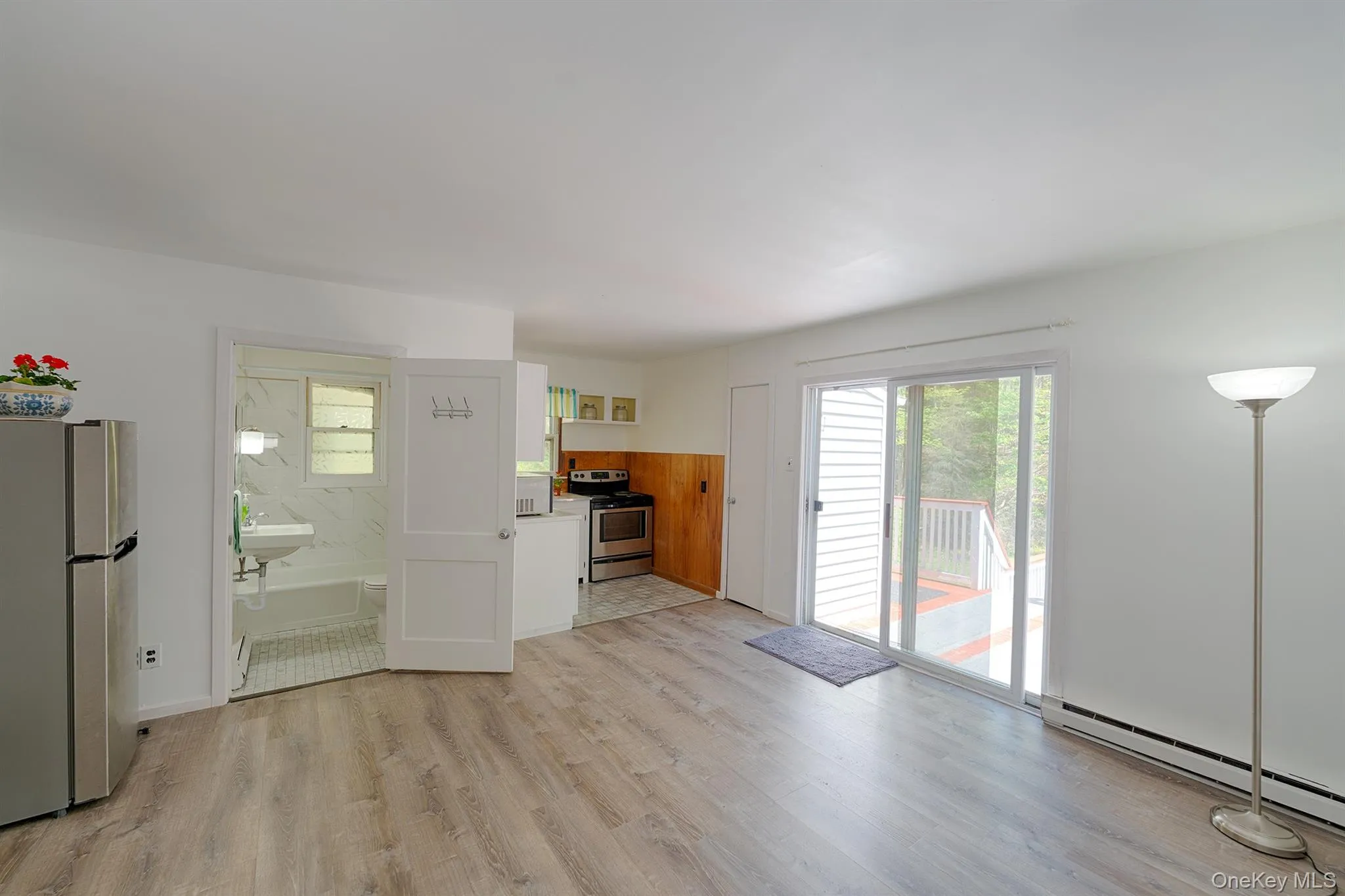 Unfurnished living room featuring a baseboard heating unit and light wood finished floors Unfurnished living room featuring a baseboard heating unit and light wood finished floors