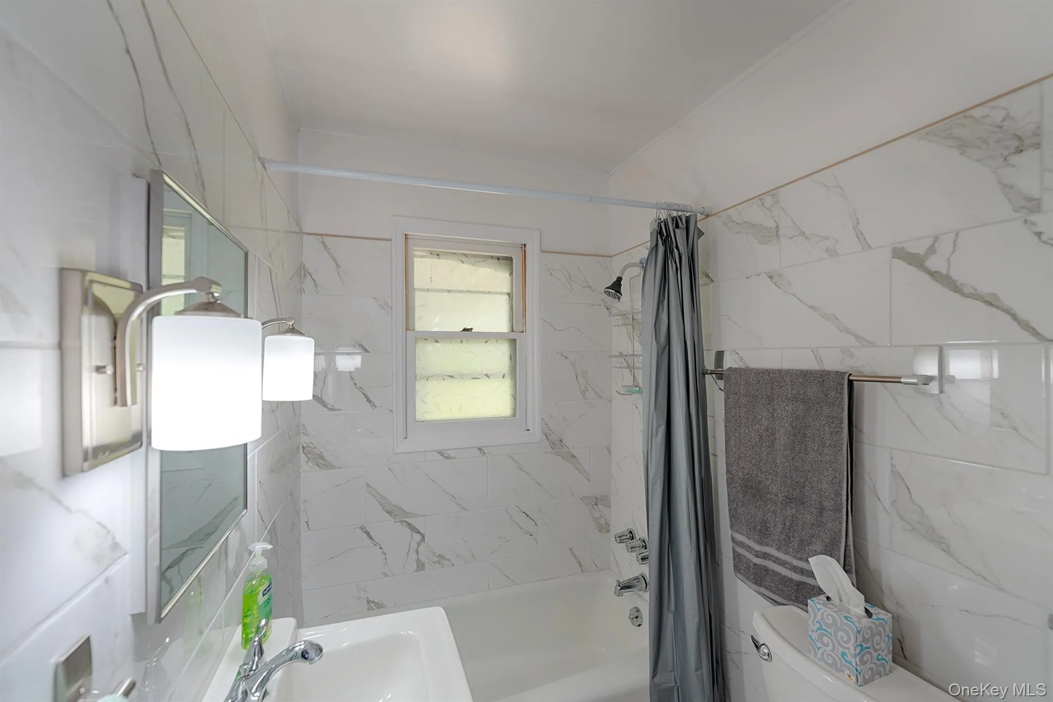 Full bath featuring toilet, shower / bath combination with curtain, and a sink Full bath featuring toilet, shower / bath combination with curtain, and a sink