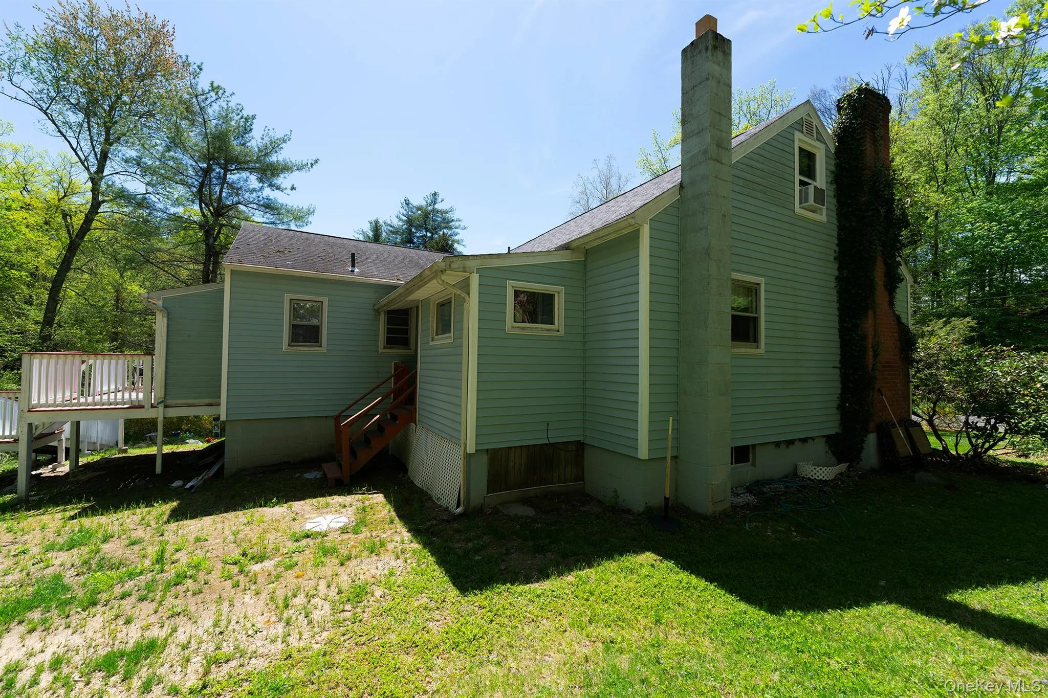 Rear view of house with a lawn, a chimney, and a deck Rear view of house with a lawn, a chimney, and a deck