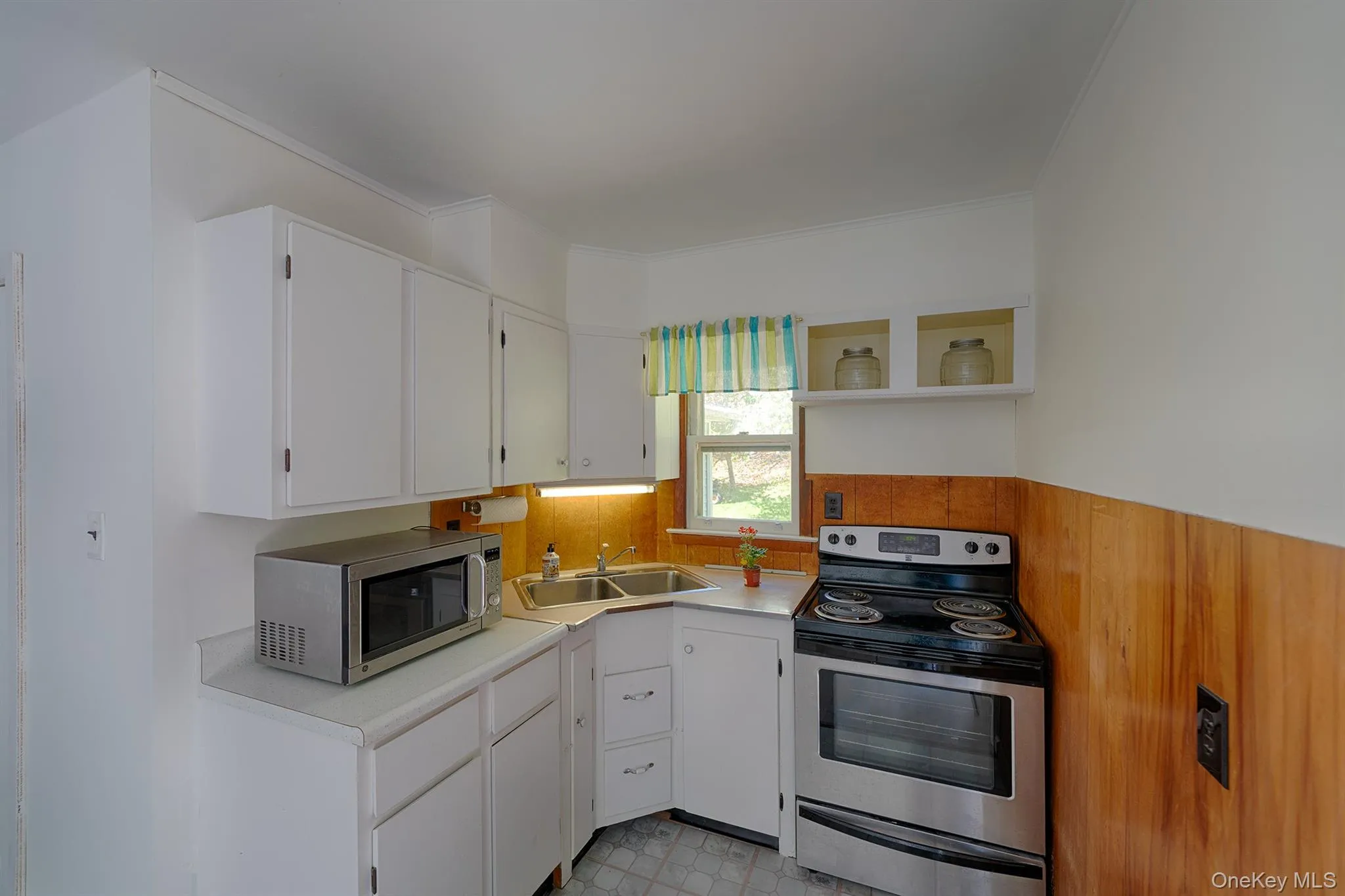 Kitchen with appliances with stainless steel finishes, a sink, light countertops, crown molding, and white cabinets Kitchen with appliances with stainless steel finishes, a sink, light countertops, crown molding, and white cabinets
