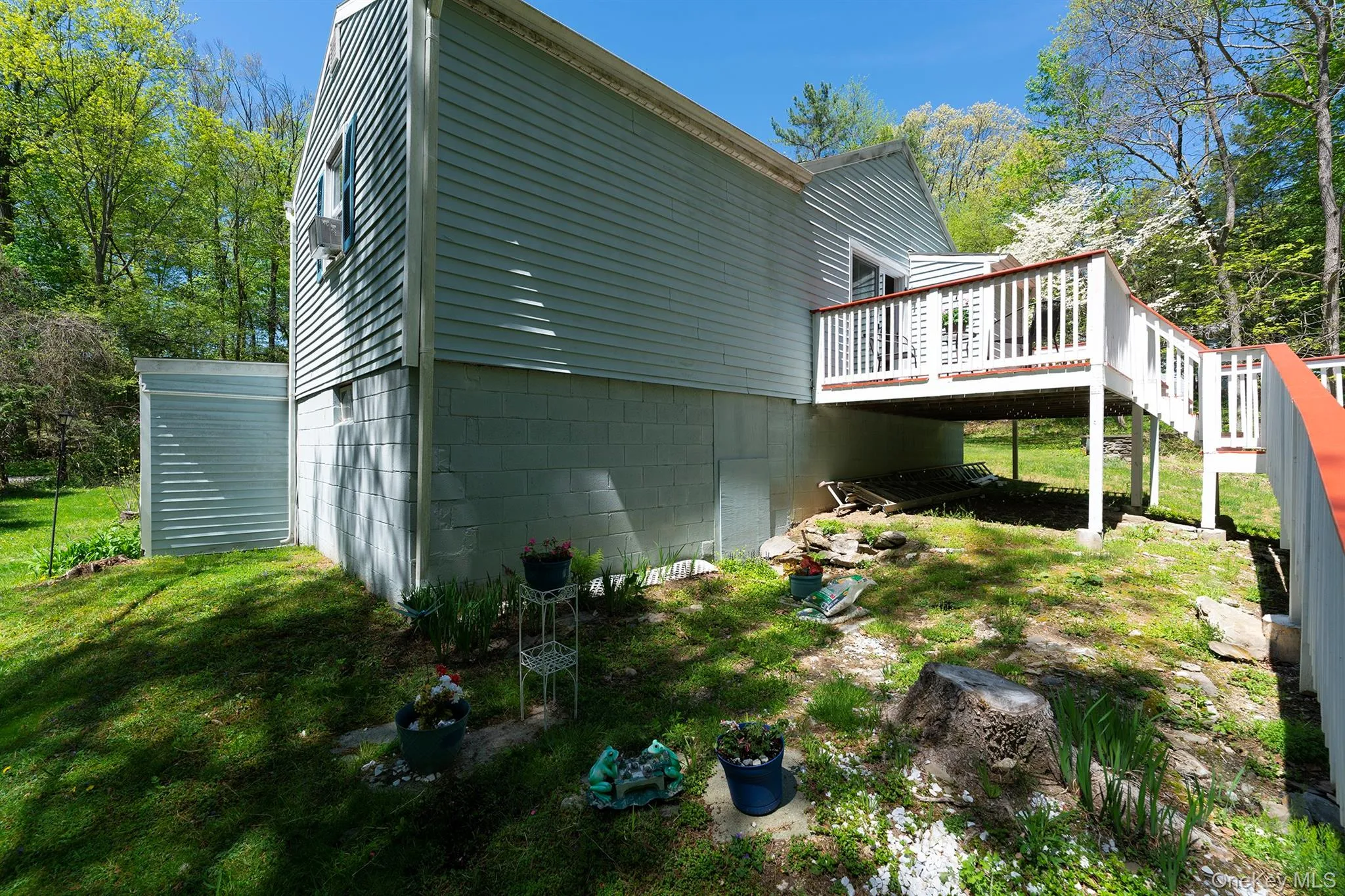 View of side of home featuring a wooden deck, a lawn, and stairway View of side of home featuring a wooden deck, a lawn, and stairway
