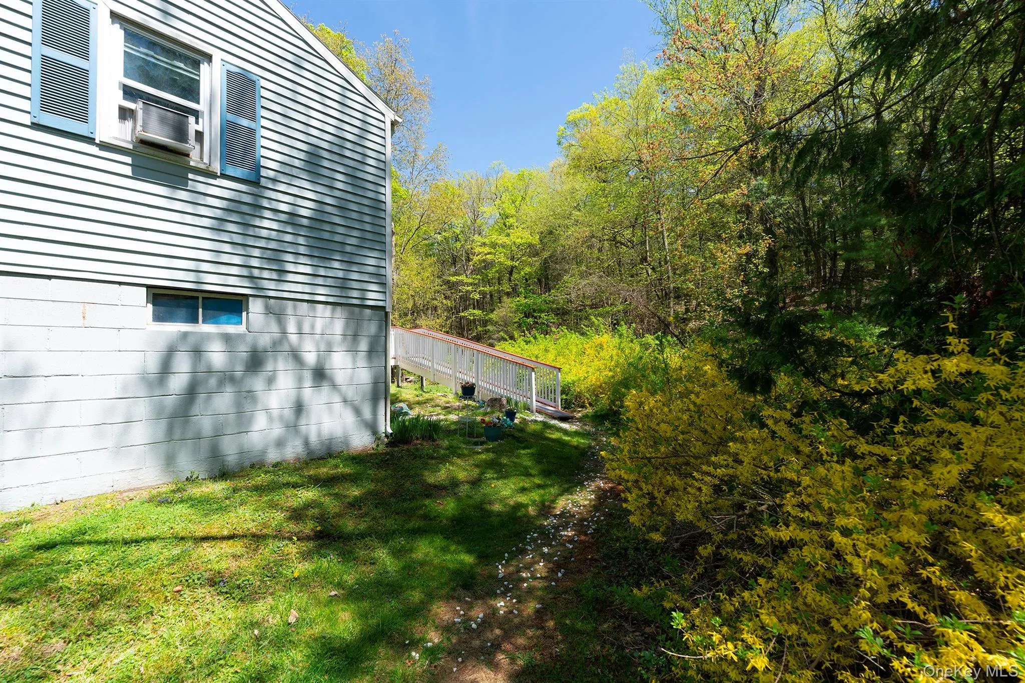 View of side of home with a yard and a wooded view View of side of home with a yard and a wooded view