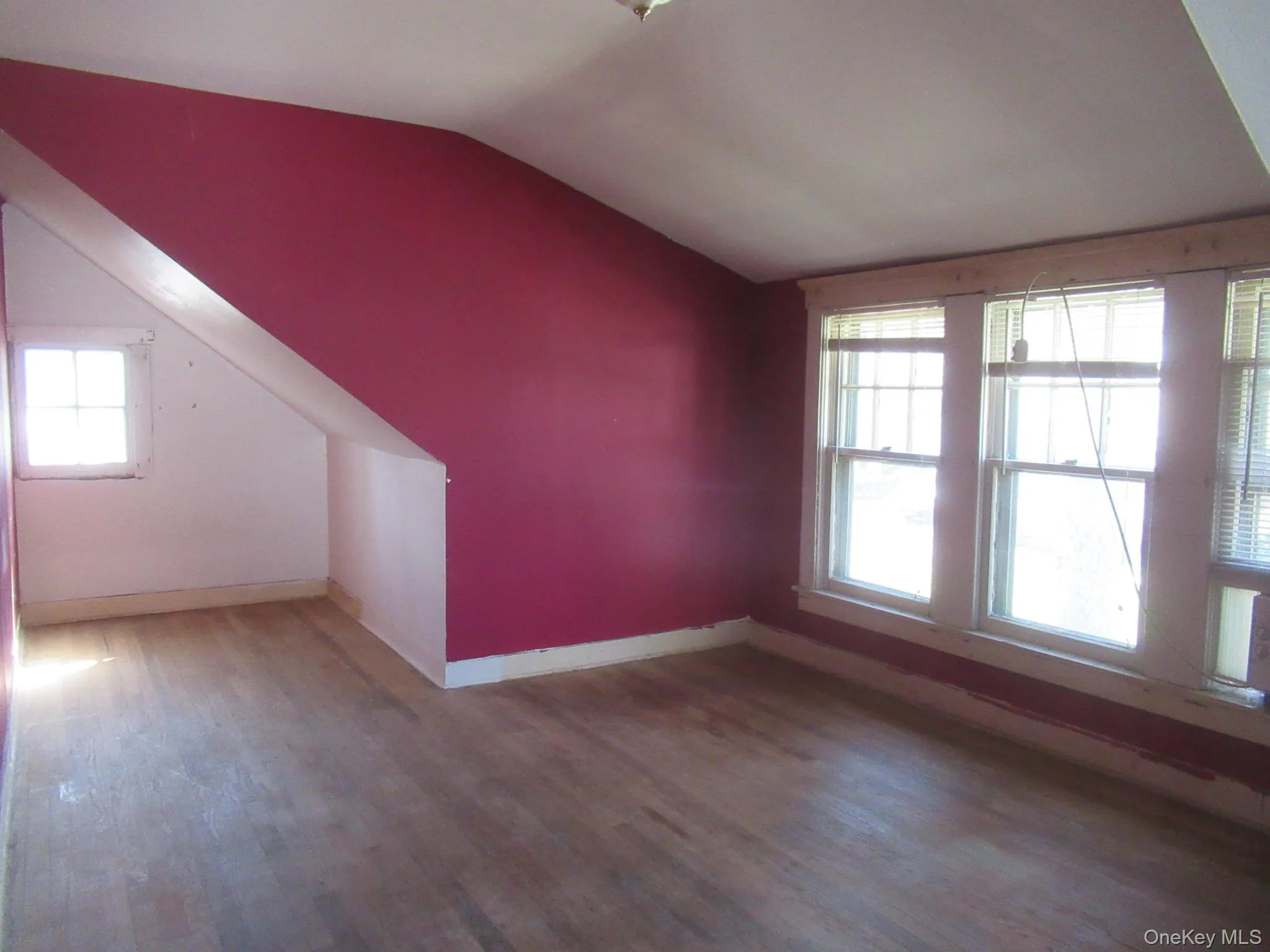 Room with wood-finish flooring, a sloped ceiling, and multiple windows Room with wood-finish flooring, a sloped ceiling, and multiple windows