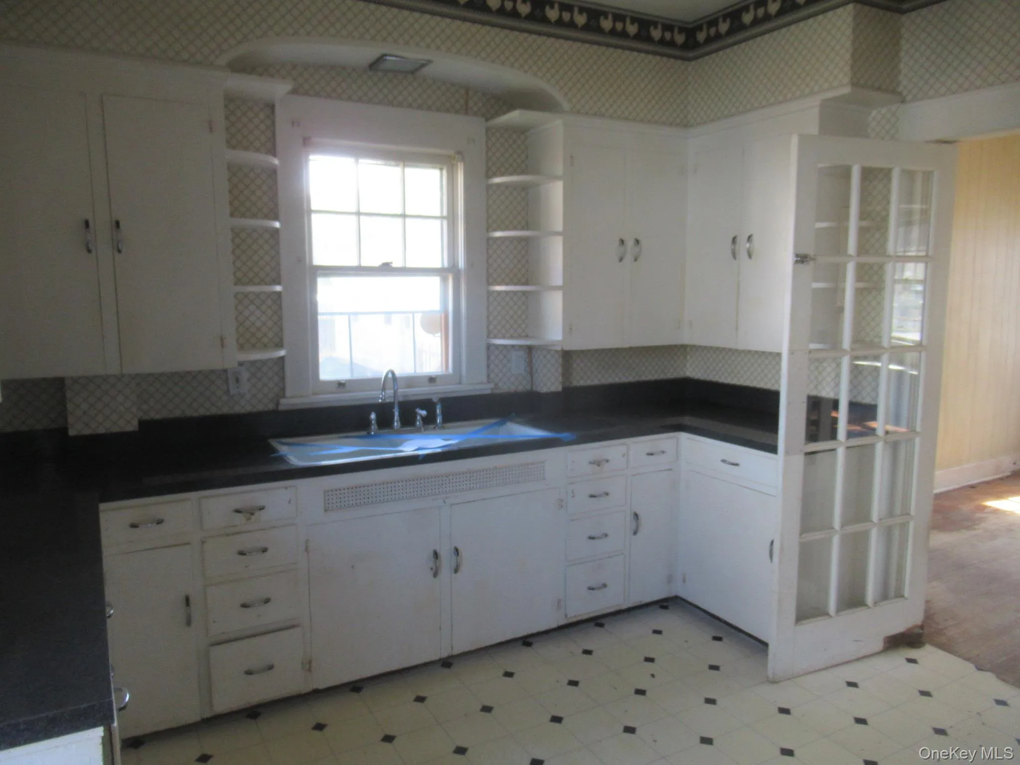 Corner kitchen featuring extensive white cabinetry with shelving,with window above the sink Corner kitchen featuring extensive white cabinetry with shelving,with window above the sink