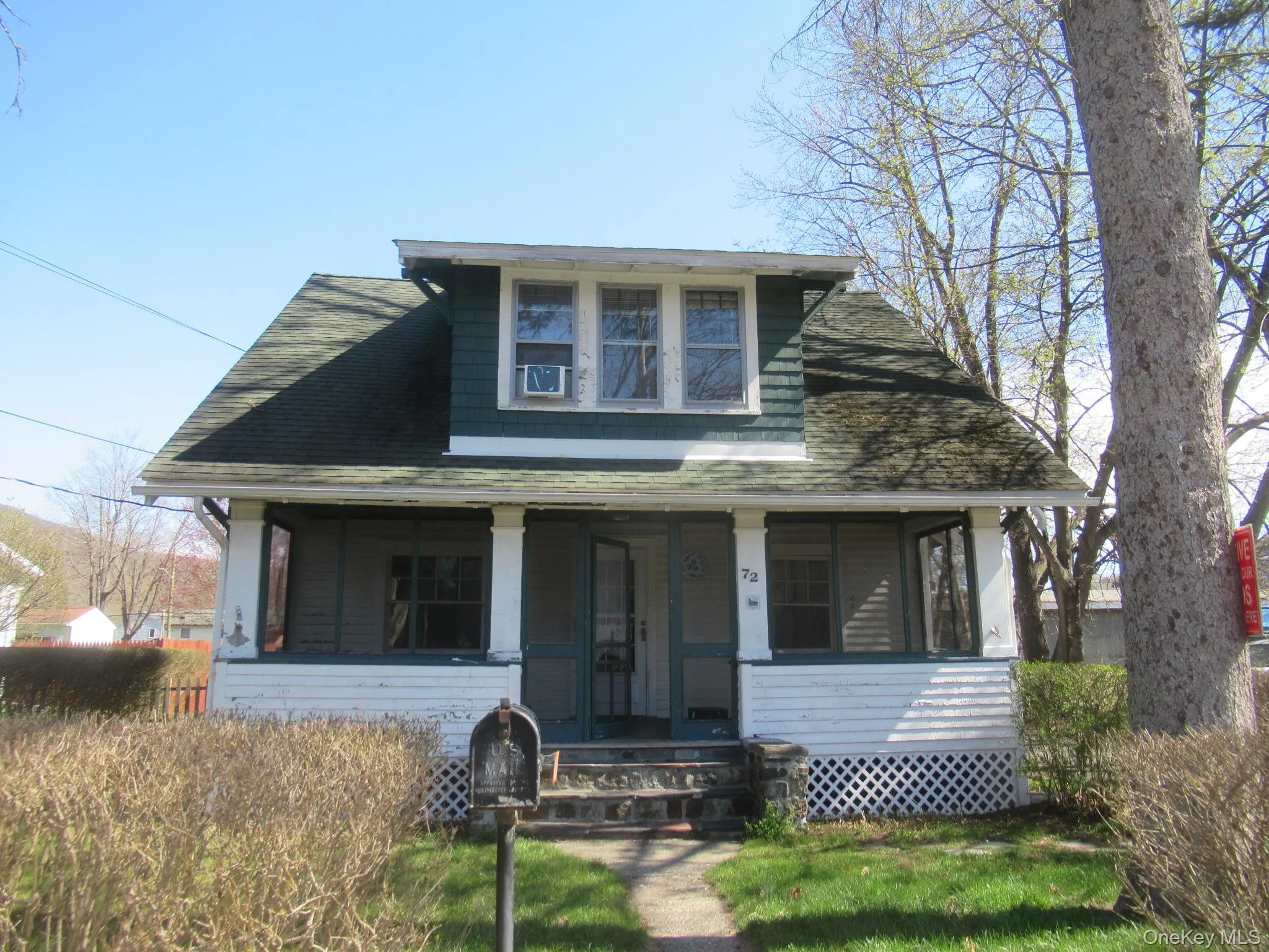 Charming residence featuring a screened-in front porch, a dormer window, and a dark green shingle roof Charming residence featuring a screened-in front porch, a dormer window, and a dark green shingle roof