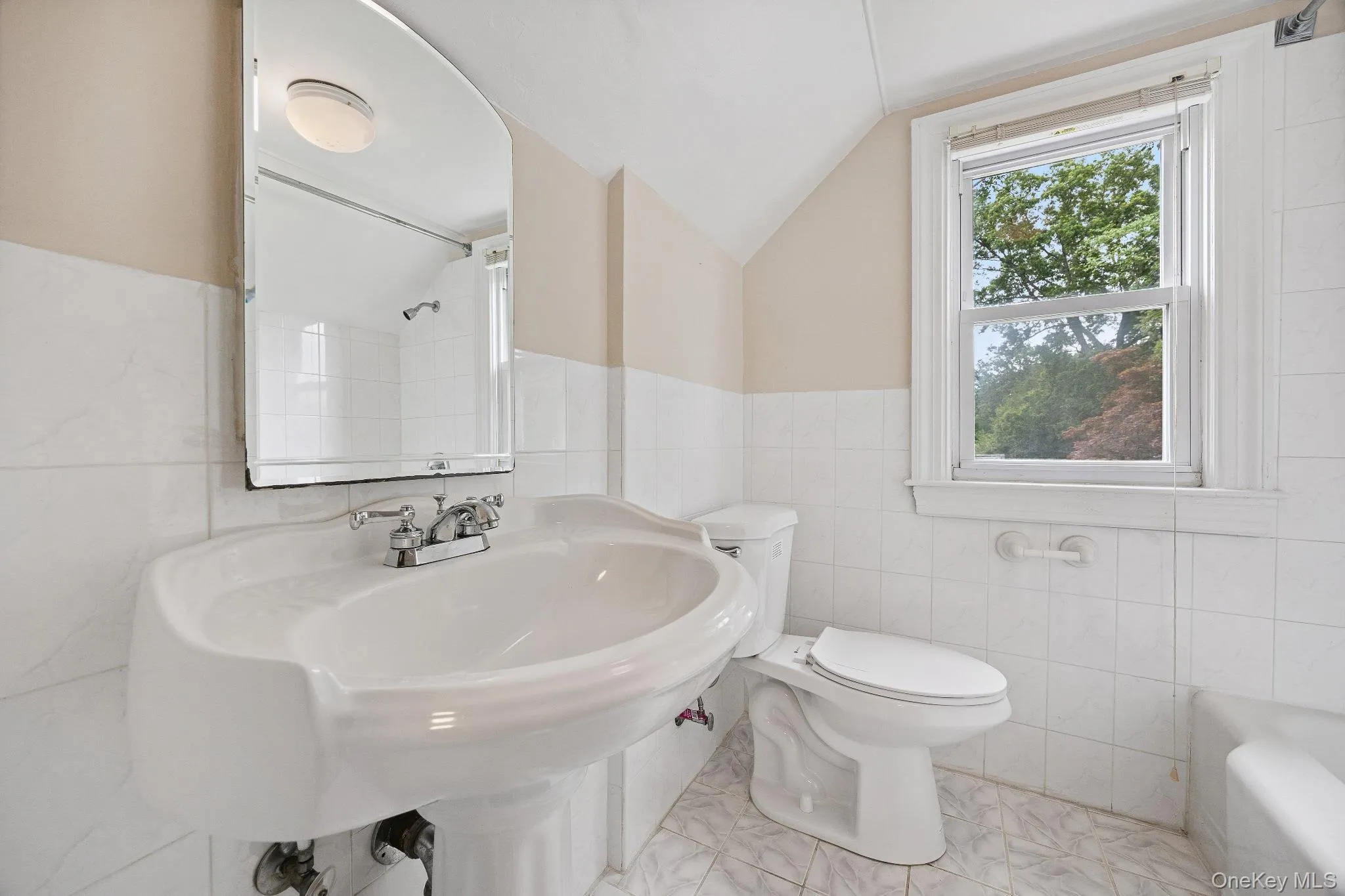 Full bathroom featuring tile walls, lofted ceiling, and a bathtub Full bathroom featuring tile walls, lofted ceiling, and a bathtub