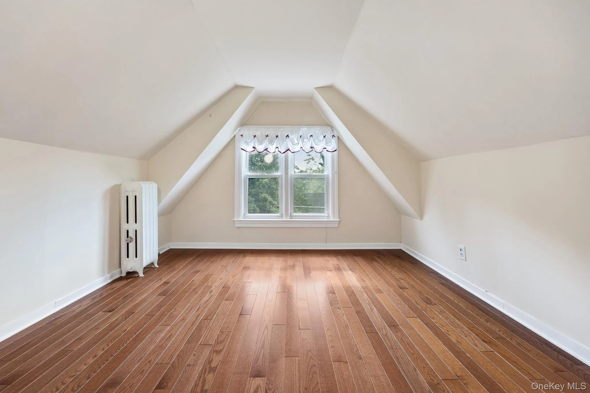 Bonus room featuring radiator, hardwood / wood-style floors, and lofted ceiling Bonus room featuring radiator, hardwood / wood-style floors, and lofted ceiling