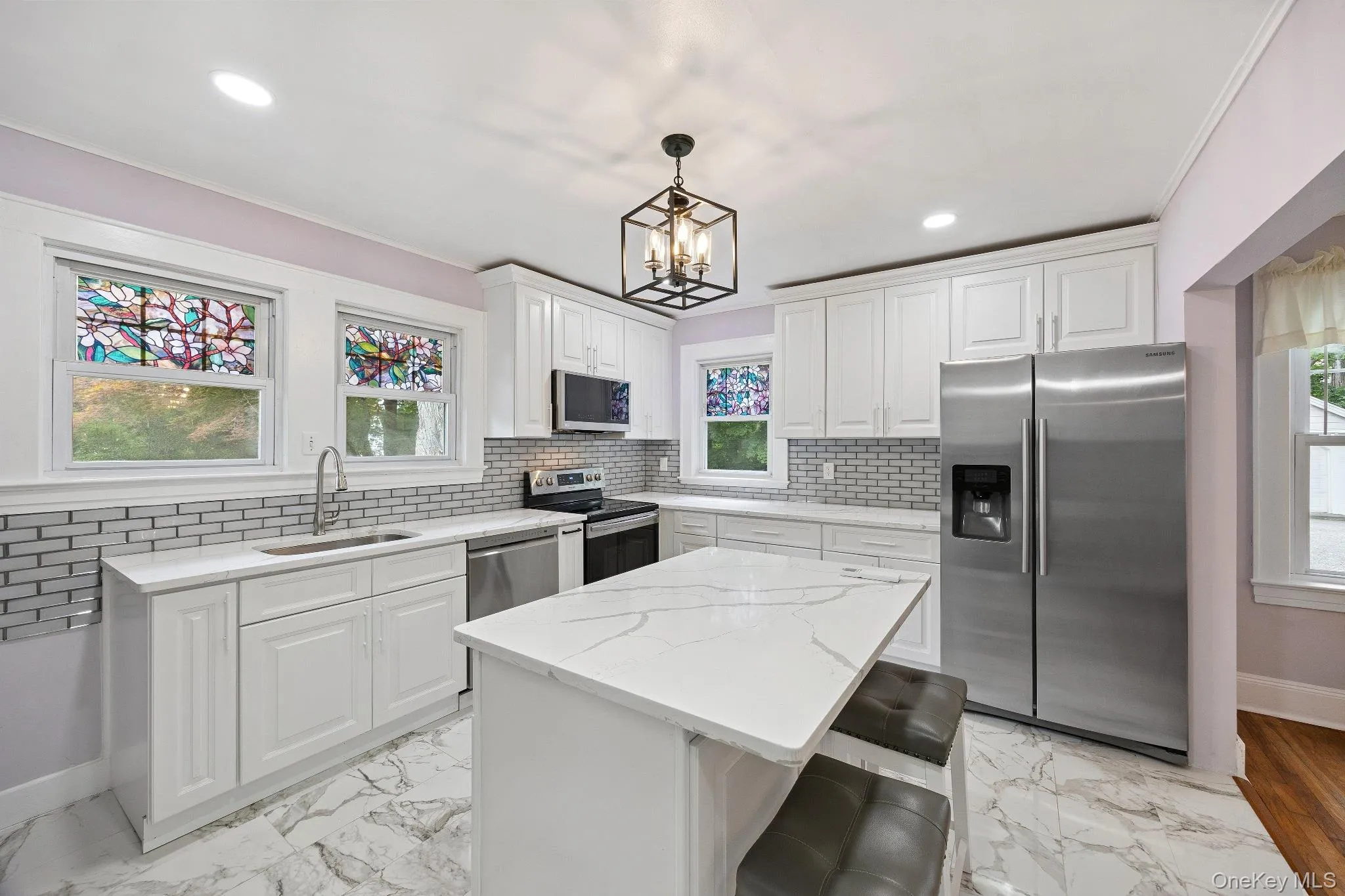 Kitchen featuring stainless steel appliances, plenty of natural light, tasteful backsplash, white cabinetry, and recessed lighting Kitchen featuring stainless steel appliances, plenty of natural light, tasteful backsplash, white cabinetry, and recessed lighting