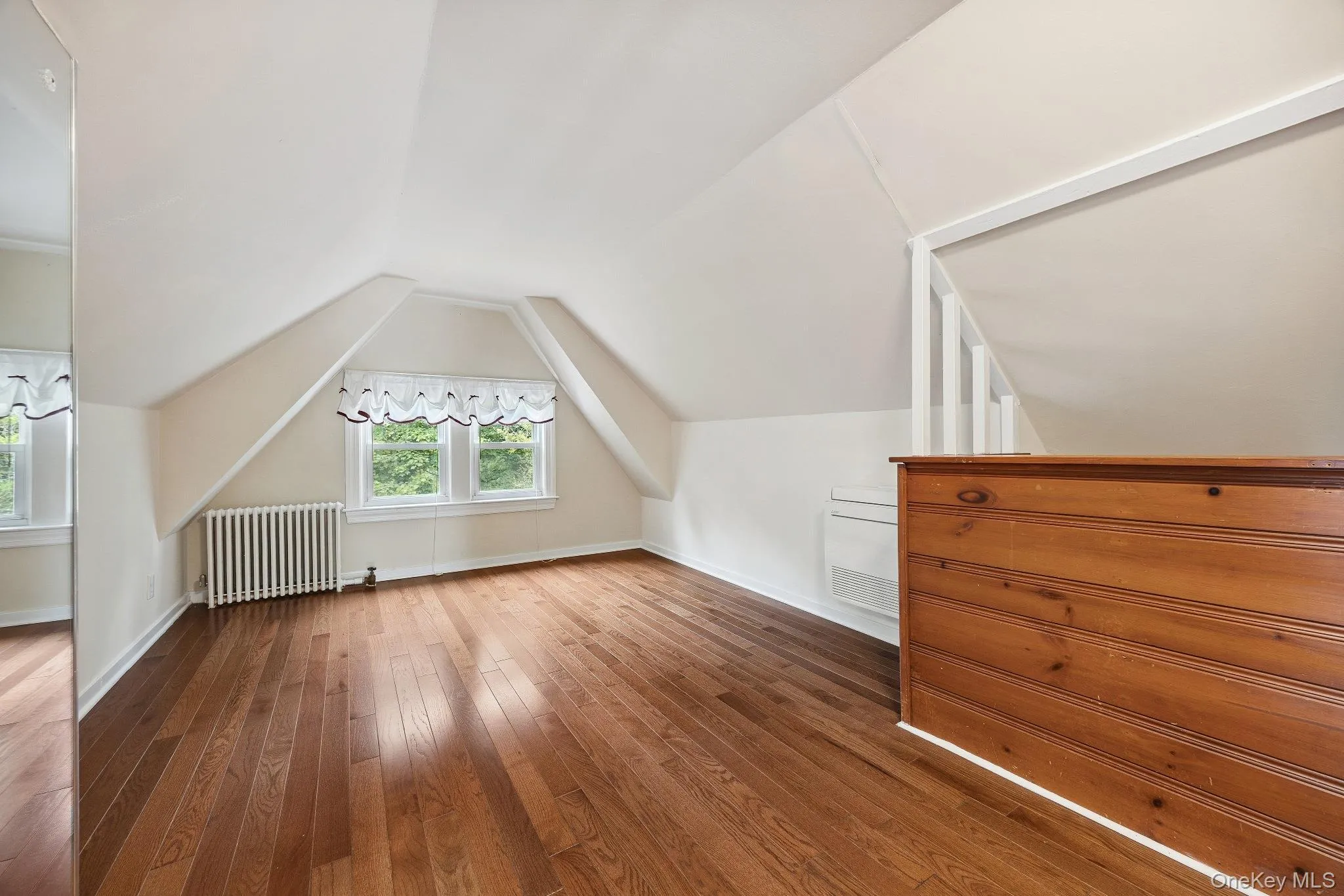 Bonus room featuring radiator heating unit, dark wood finished floors, and vaulted ceiling Bonus room featuring radiator heating unit, dark wood finished floors, and vaulted ceiling