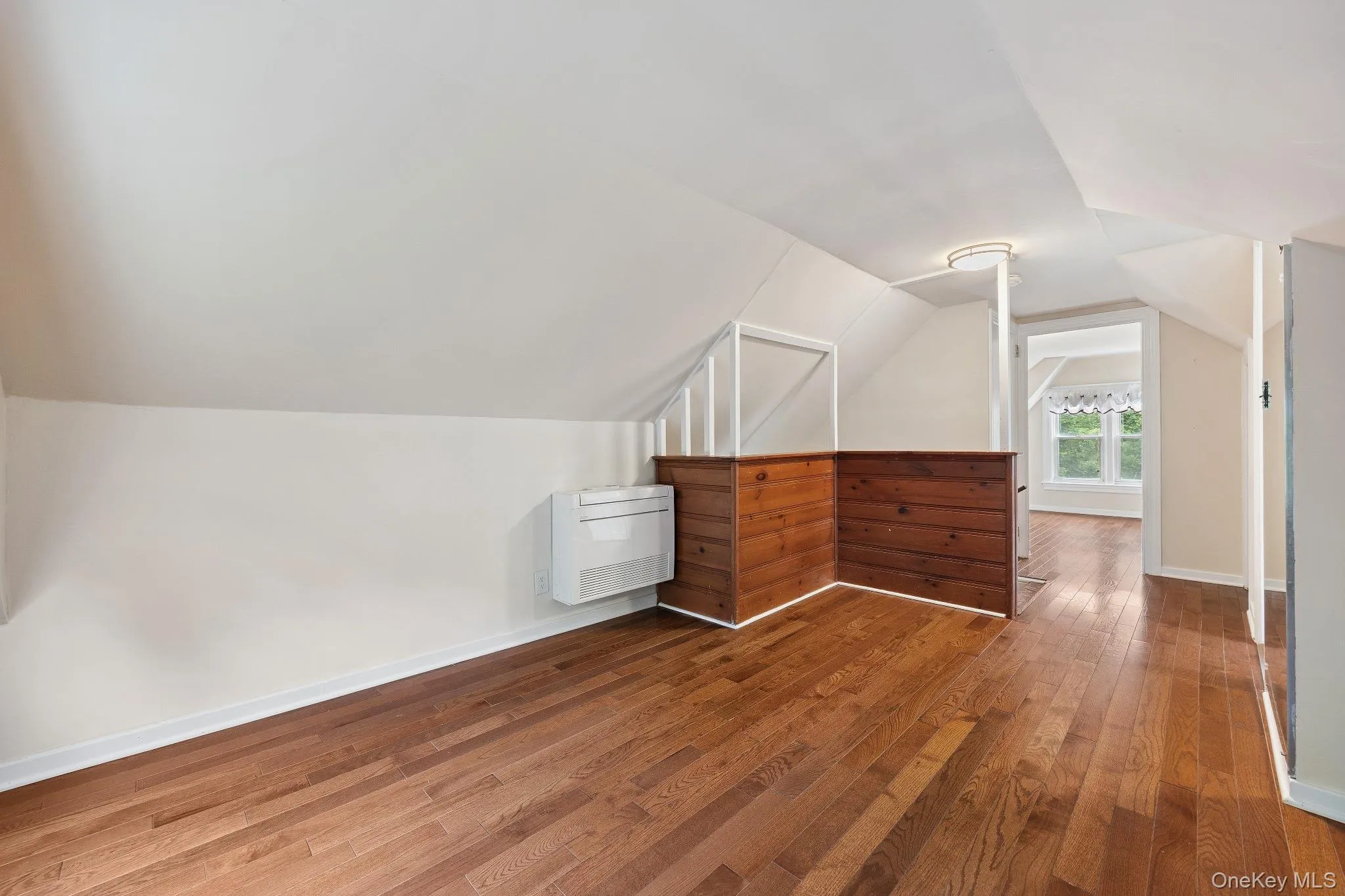 Additional living space with hardwood / wood-style flooring, heating unit, and lofted ceiling Additional living space with hardwood / wood-style flooring, heating unit, and lofted ceiling
