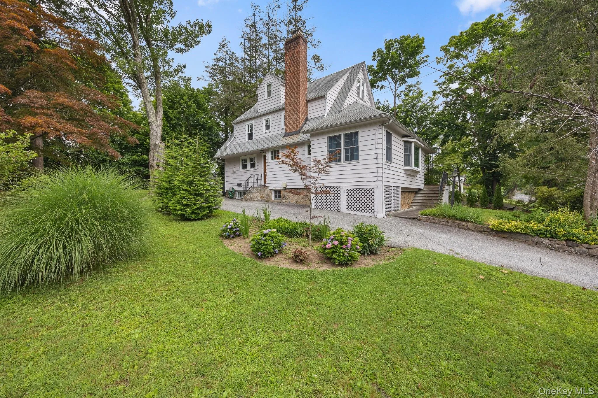 View of side of home with a chimney, asphalt driveway, a lawn, and stairway View of side of home with a chimney, asphalt driveway, a lawn, and stairway
