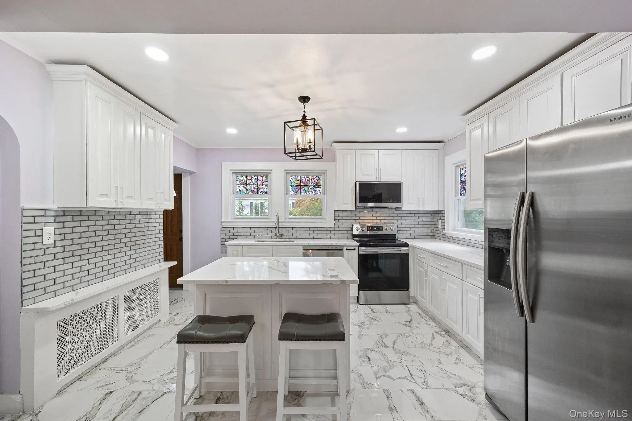 Kitchen with stainless steel appliances, light marble finish floors, white cabinets, recessed lighting, and ornamental molding Kitchen with stainless steel appliances, light marble finish floors, white cabinets, recessed lighting, and ornamental molding