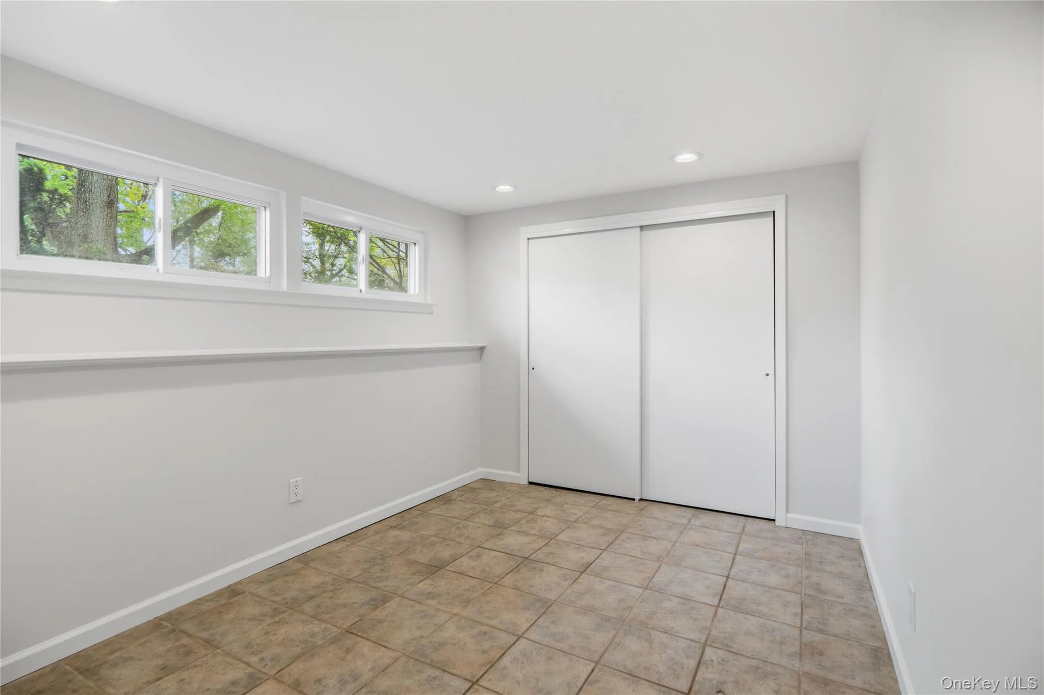 Room featuring light gray walls, transom windows, recessed lighting, and tile flooring Room featuring light gray walls, transom windows, recessed lighting, and tile flooring