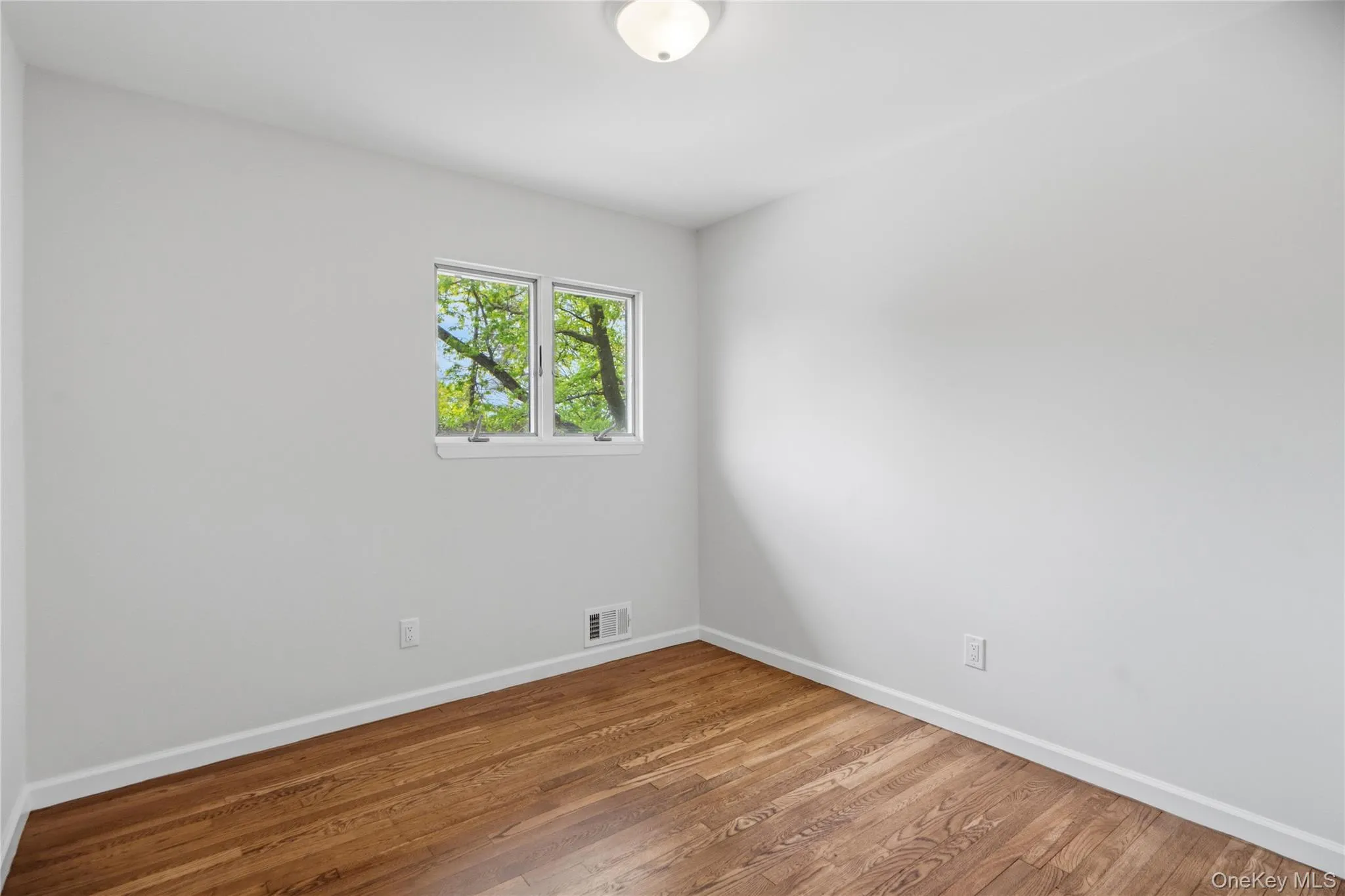 Third Bedroom with Bright interior with hardwood flooring, white baseboards, and a flush-mount ceiling light fixture Third Bedroom with Bright interior with hardwood flooring, white baseboards, and a flush-mount ceiling light fixture