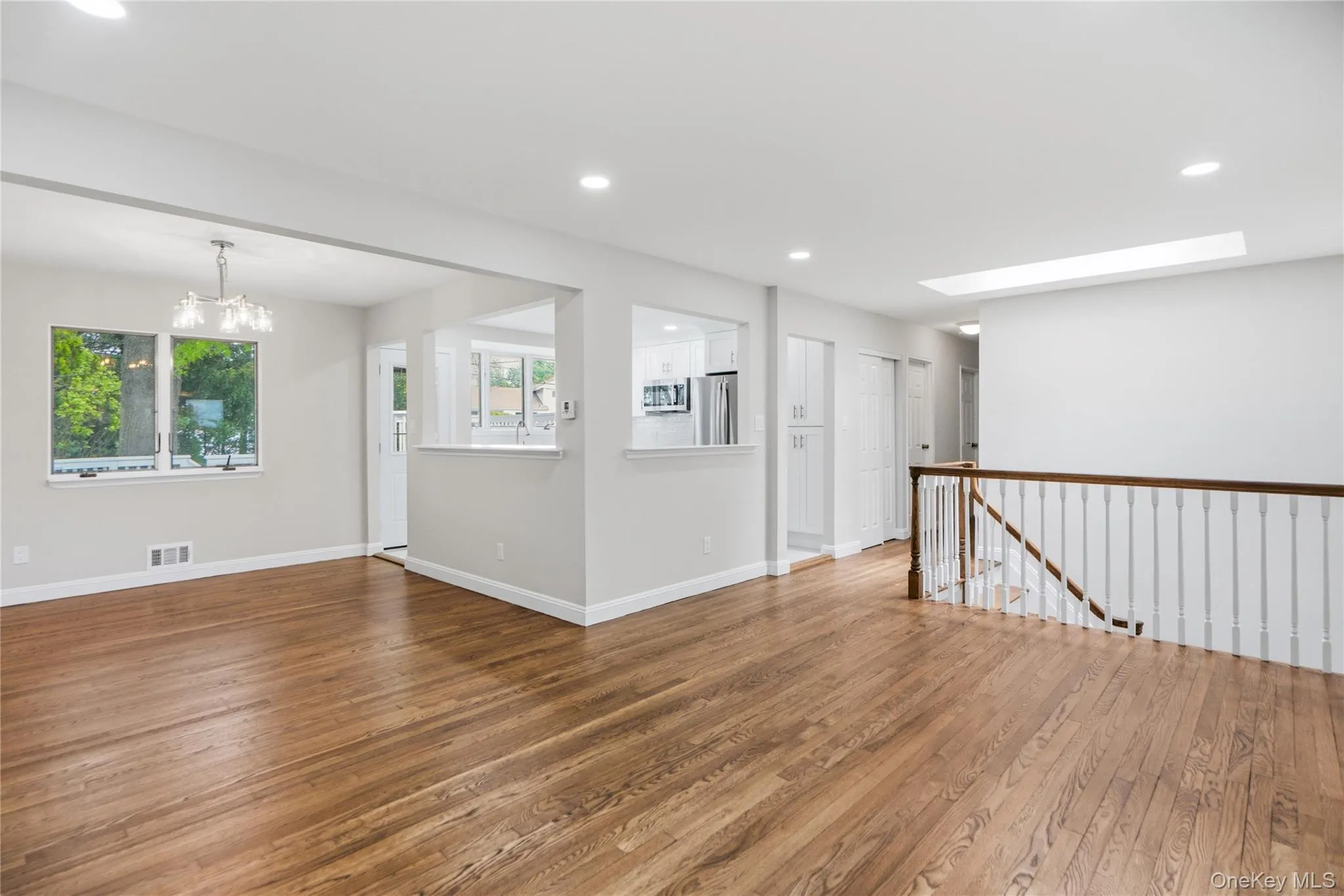 Spacious living area featuring rich wood-finish flooring, recessed lighting, and a skylight Spacious living area featuring rich wood-finish flooring, recessed lighting, and a skylight
