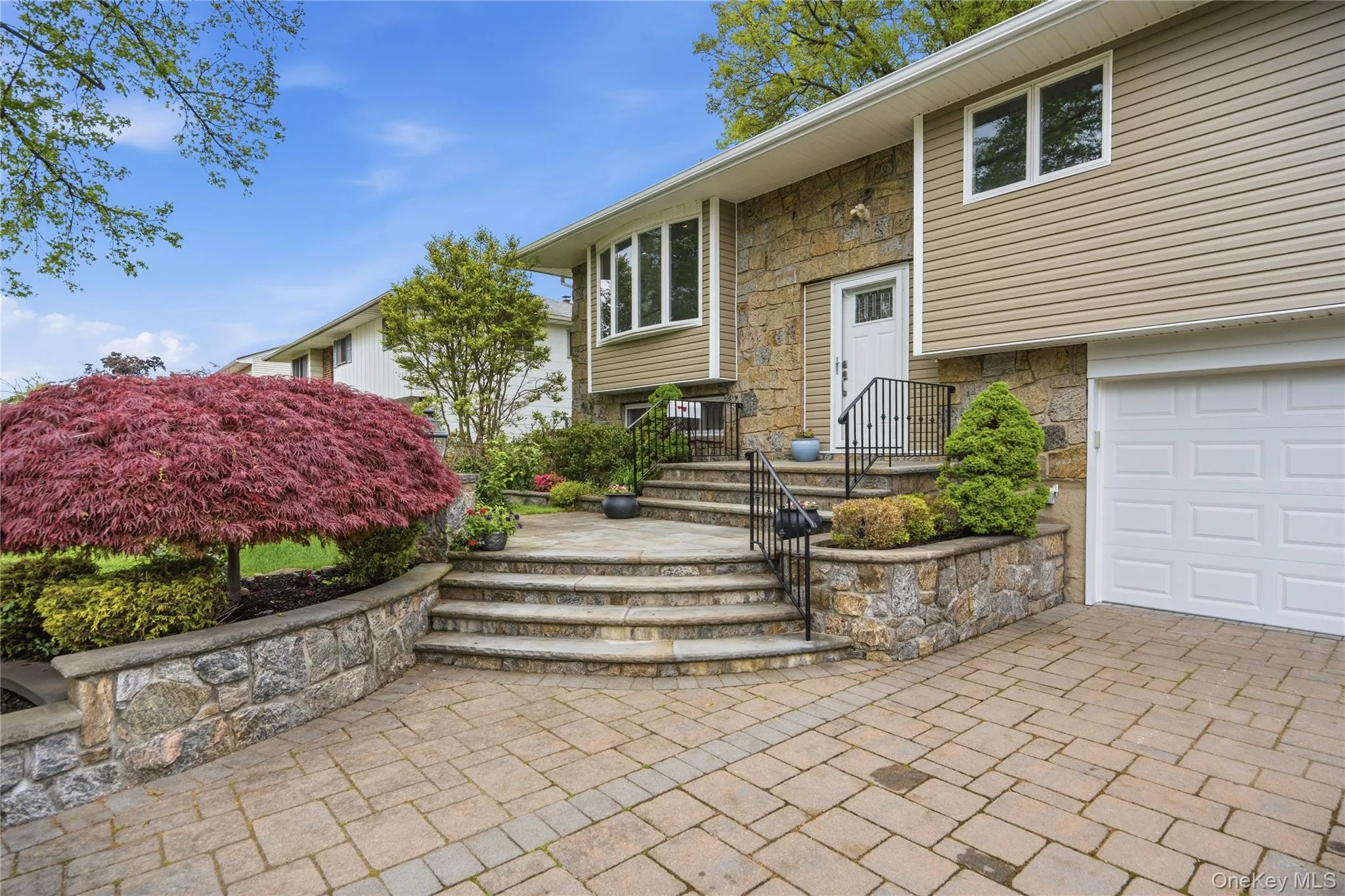 Close up of Residence with light stone steps, Paver driveway with new garage doors Close up of Residence with light stone steps, Paver driveway with new garage doors