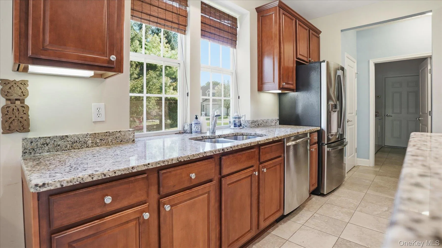 Kitchen featuring rich wood cabinetry, light-toned granite countertops, a double basin sink with a chrome faucet Kitchen featuring rich wood cabinetry, light-toned granite countertops, a double basin sink with a chrome faucet