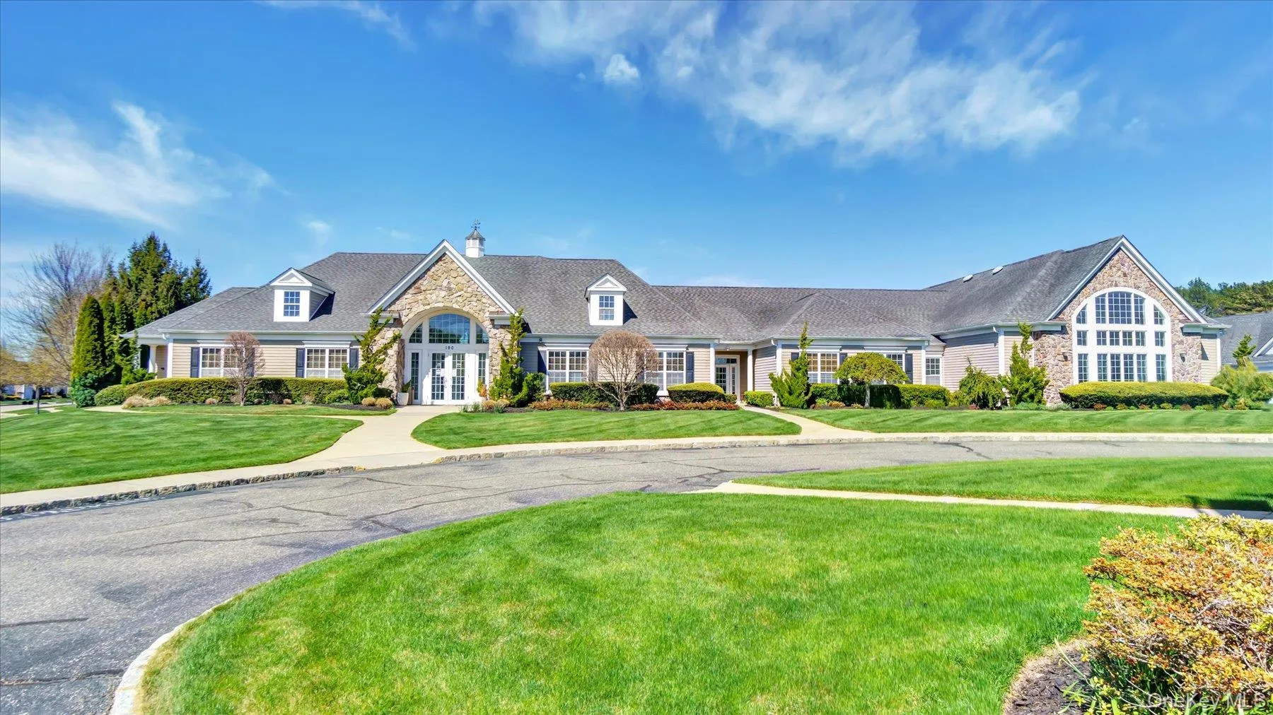 Club House with exterior facade featuring stone accents, multiple dormer windows, and a prominent arched window design Club House with exterior facade featuring stone accents, multiple dormer windows, and a prominent arched window design