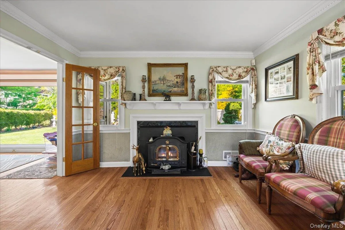 Living area featuring a traditional wood-burning stove with a stone hearth, set against a classic white mantel Living area featuring a traditional wood-burning stove with a stone hearth, set against a classic white mantel
