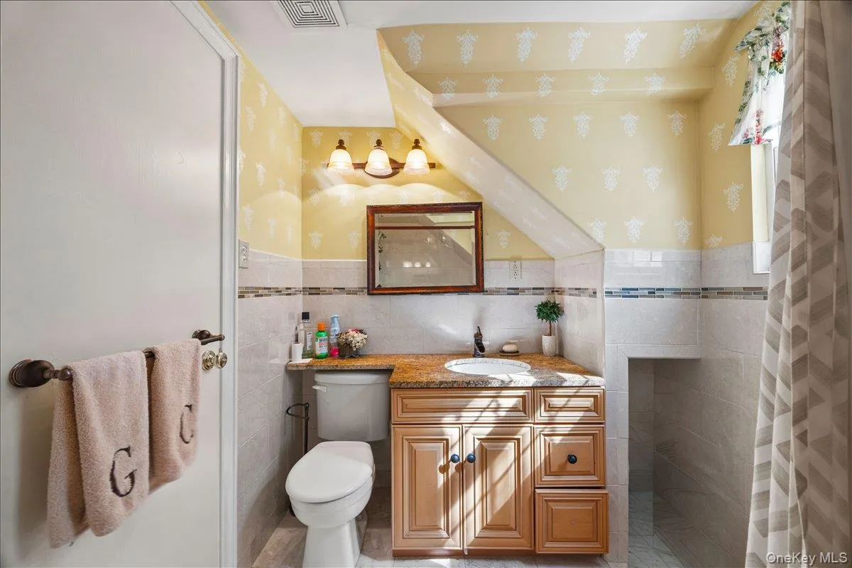 Bathroom featuring a built-in vanity with a granite-style countertop, undermount sink, and wood cabinetry Bathroom featuring a built-in vanity with a granite-style countertop, undermount sink, and wood cabinetry
