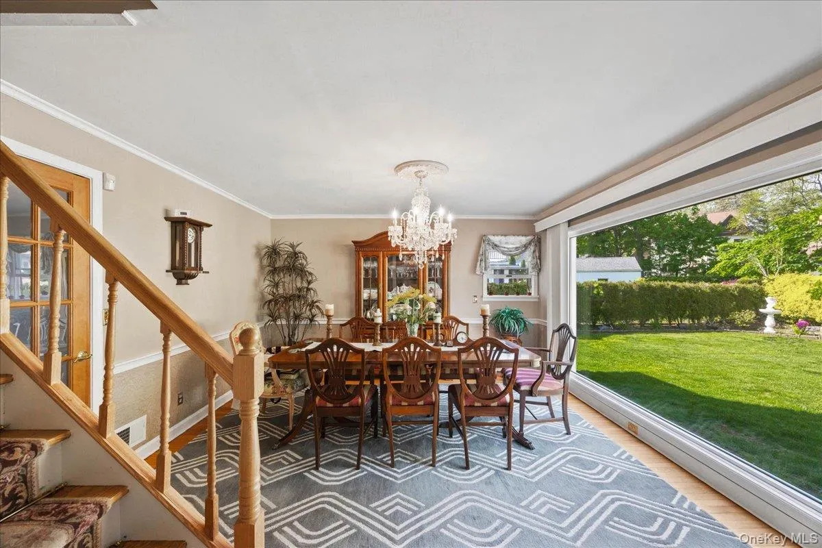 Dining area featuring wood-finish flooring, a chandelier with ceiling medallion, and a large picture window overlooking a green lawn Dining area featuring wood-finish flooring, a chandelier with ceiling medallion, and a large picture window overlooking a green lawn