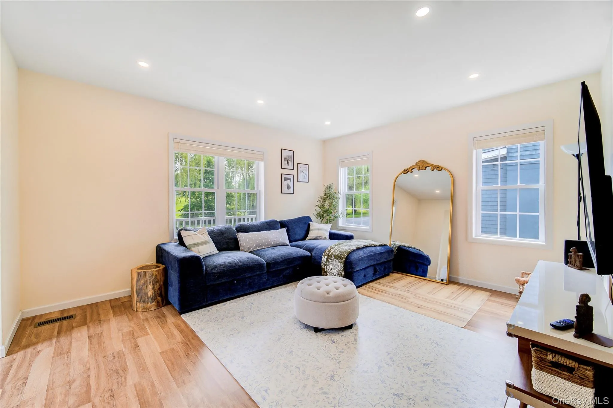 Spacious room featuring wood-finish flooring, recessed ceiling lighting, and multiple windows Spacious room featuring wood-finish flooring, recessed ceiling lighting, and multiple windows