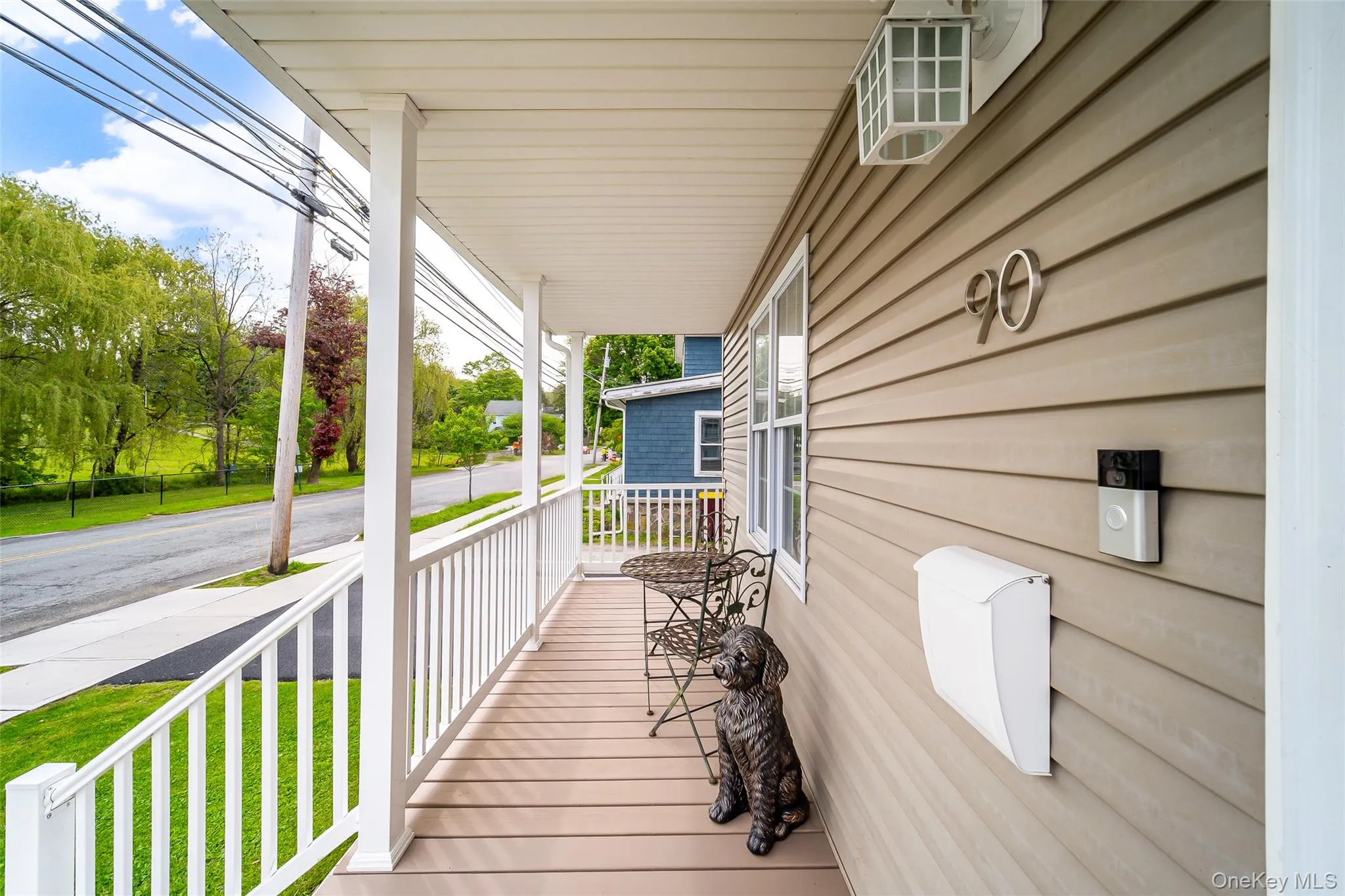 Covered front porch featuring wood-finish decking, white railings, and a matching white ceiling Covered front porch featuring wood-finish decking, white railings, and a matching white ceiling