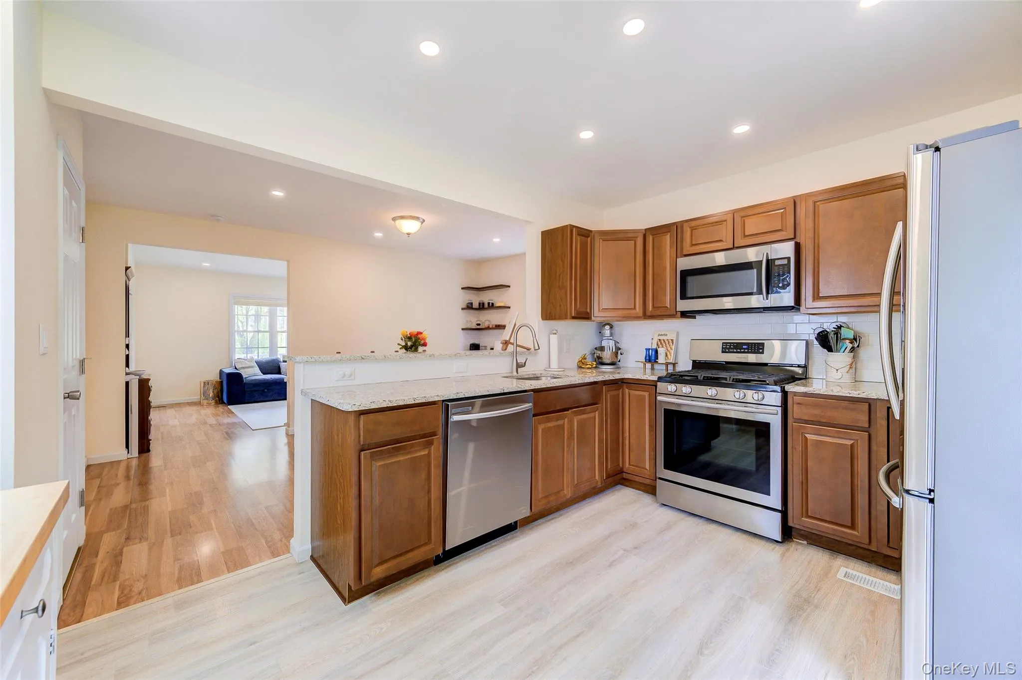 Modern kitchen featuring wood-finish cabinetry, stainless steel appliances, granite-style countertops, and a subway tile backsplash Modern kitchen featuring wood-finish cabinetry, stainless steel appliances, granite-style countertops, and a subway tile backsplash