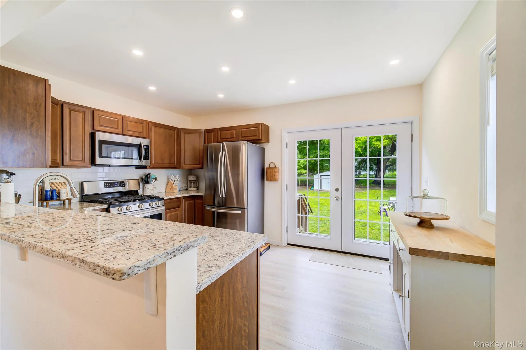 Kitchen featuring wood cabinetry, stainless steel appliances, speckled stone countertops, and recessed lighting Kitchen featuring wood cabinetry, stainless steel appliances, speckled stone countertops, and recessed lighting