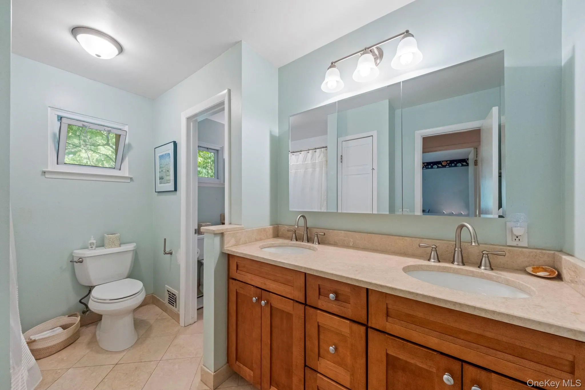 Bathroom featuring a double vanity with wood cabinetry, light-toned countertop, and undermount sinks. This bathroom has a bathtub/shower Bathroom featuring a double vanity with wood cabinetry, light-toned countertop, and undermount sinks. This bathroom has a bathtub/shower