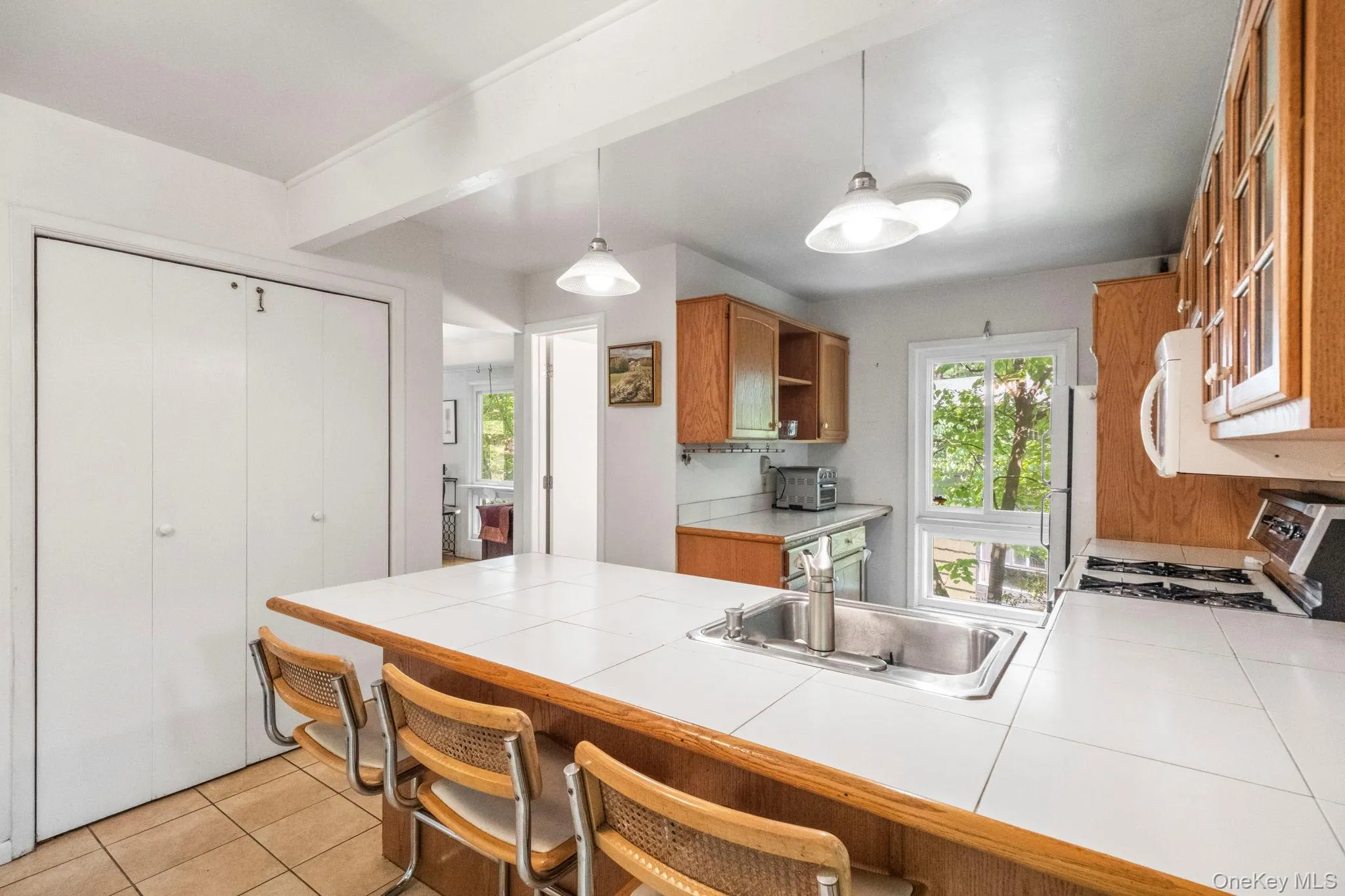 Kitchen featuring wood cabinetry, a tiled island with an integrated sink, and recessed lighting Kitchen featuring wood cabinetry, a tiled island with an integrated sink, and recessed lighting