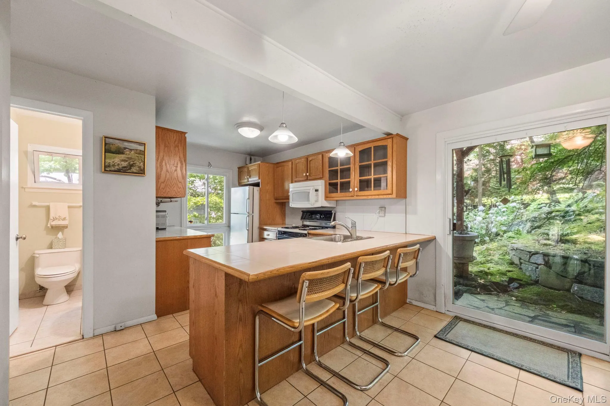 Kitchen featuring wood cabinetry, a breakfast bar, and sliding glass door to the back patio and garden Kitchen featuring wood cabinetry, a breakfast bar, and sliding glass door to the back patio and garden