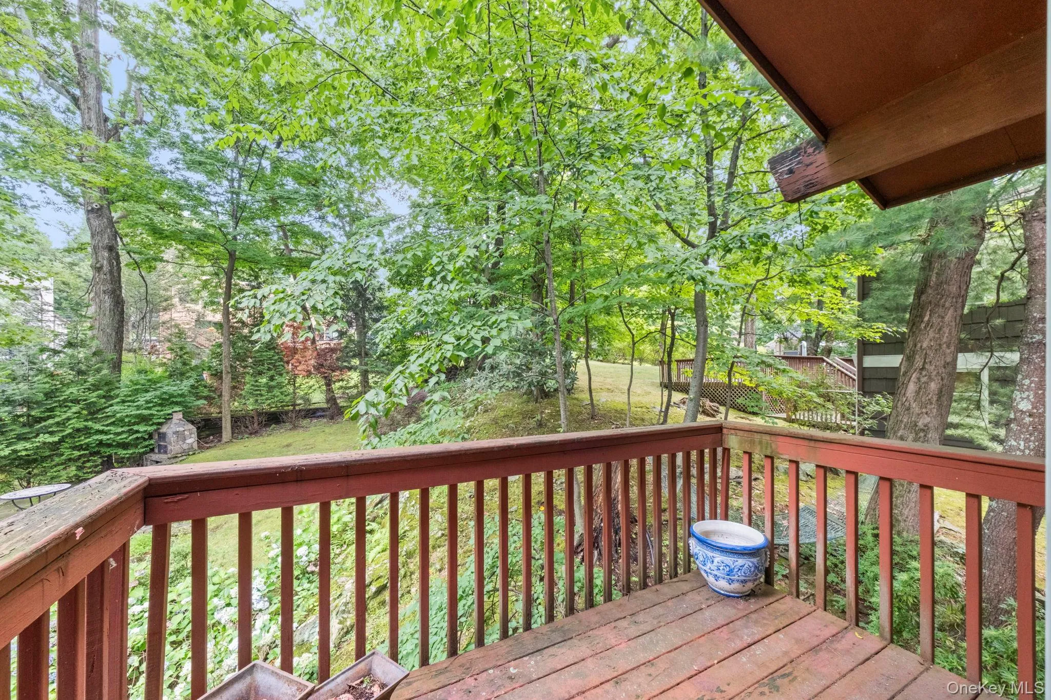 Wood deck with red railings overlooking a wooded landscape and sloped lawn Wood deck with red railings overlooking a wooded landscape and sloped lawn