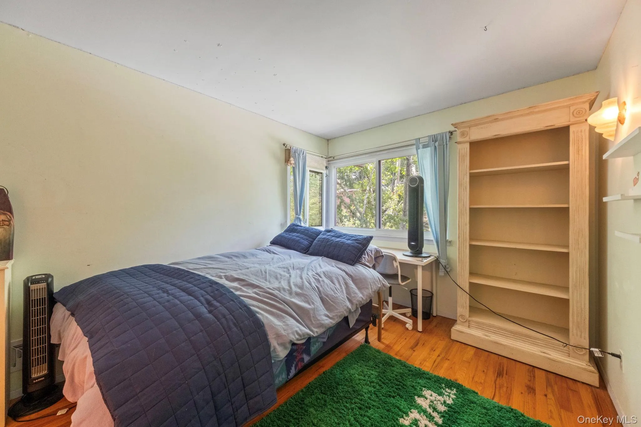 Upstairs bedroom featuring hardwood flooring, a bookshelf, and a corner window Upstairs bedroom featuring hardwood flooring, a bookshelf, and a corner window