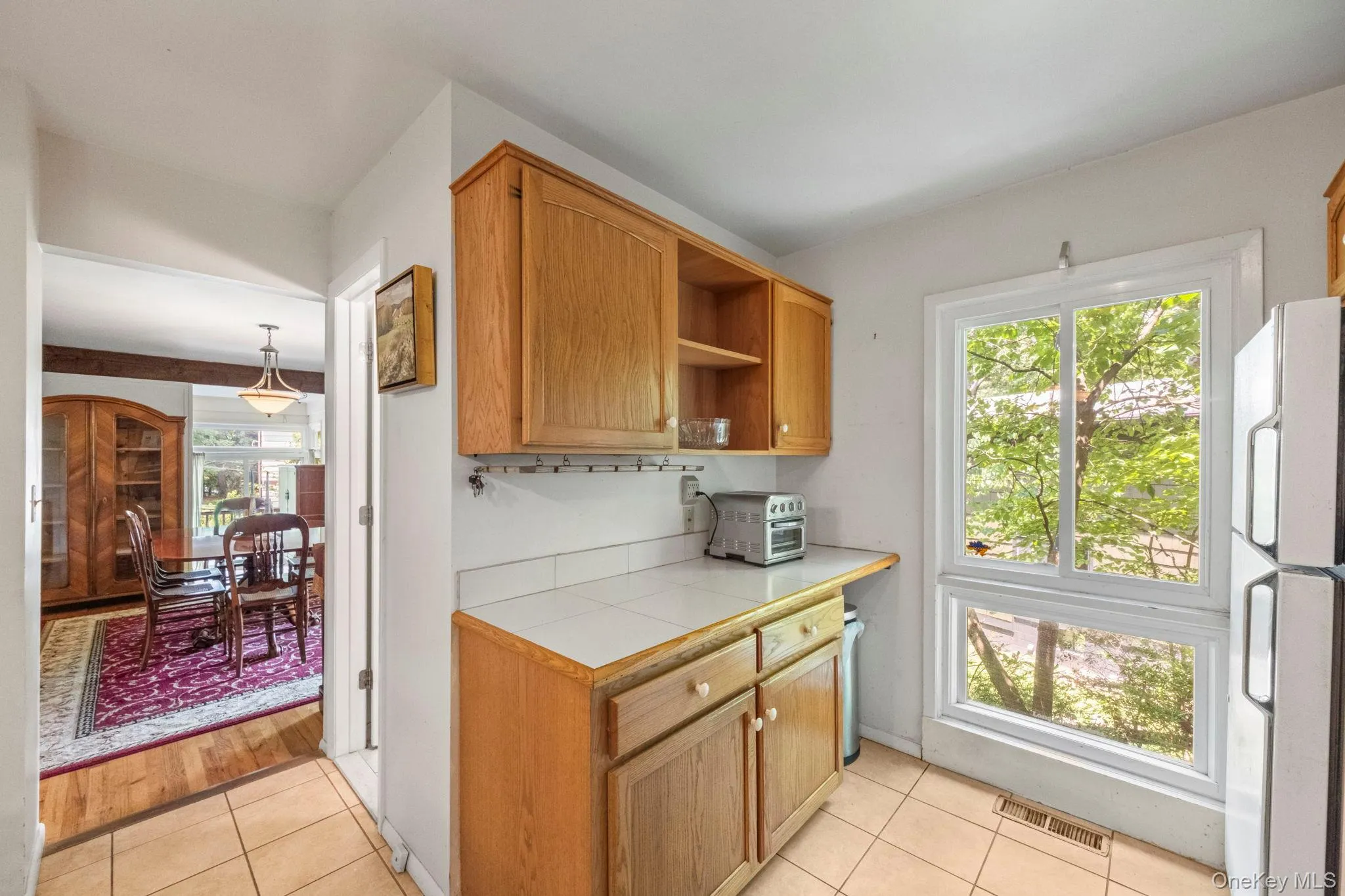 Kitchen featuring light wood cabinetry, white tile countertops, and a white tile backsplash Kitchen featuring light wood cabinetry, white tile countertops, and a white tile backsplash