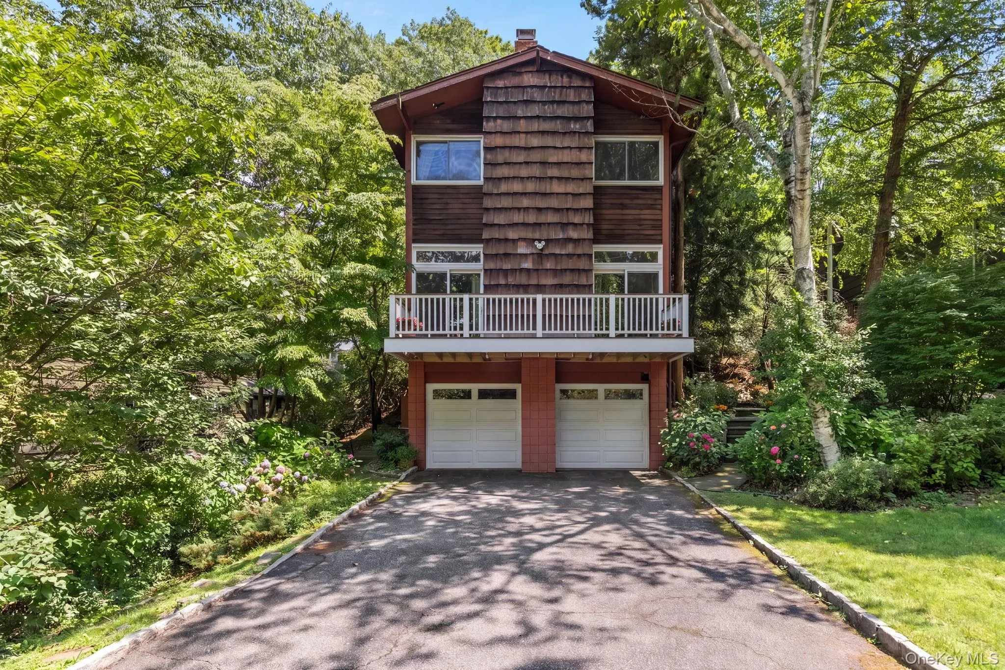 Multi-level home featuring a wood shingle exterior, balcony, and a two-car garage Multi-level home featuring a wood shingle exterior, balcony, and a two-car garage